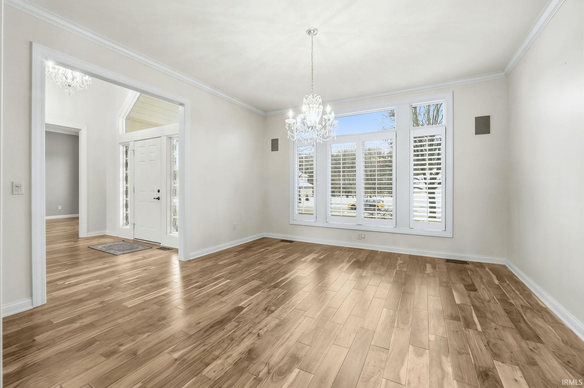 Unfurnished dining area featuring a chandelier, light wood-type flooring, and ornamental molding