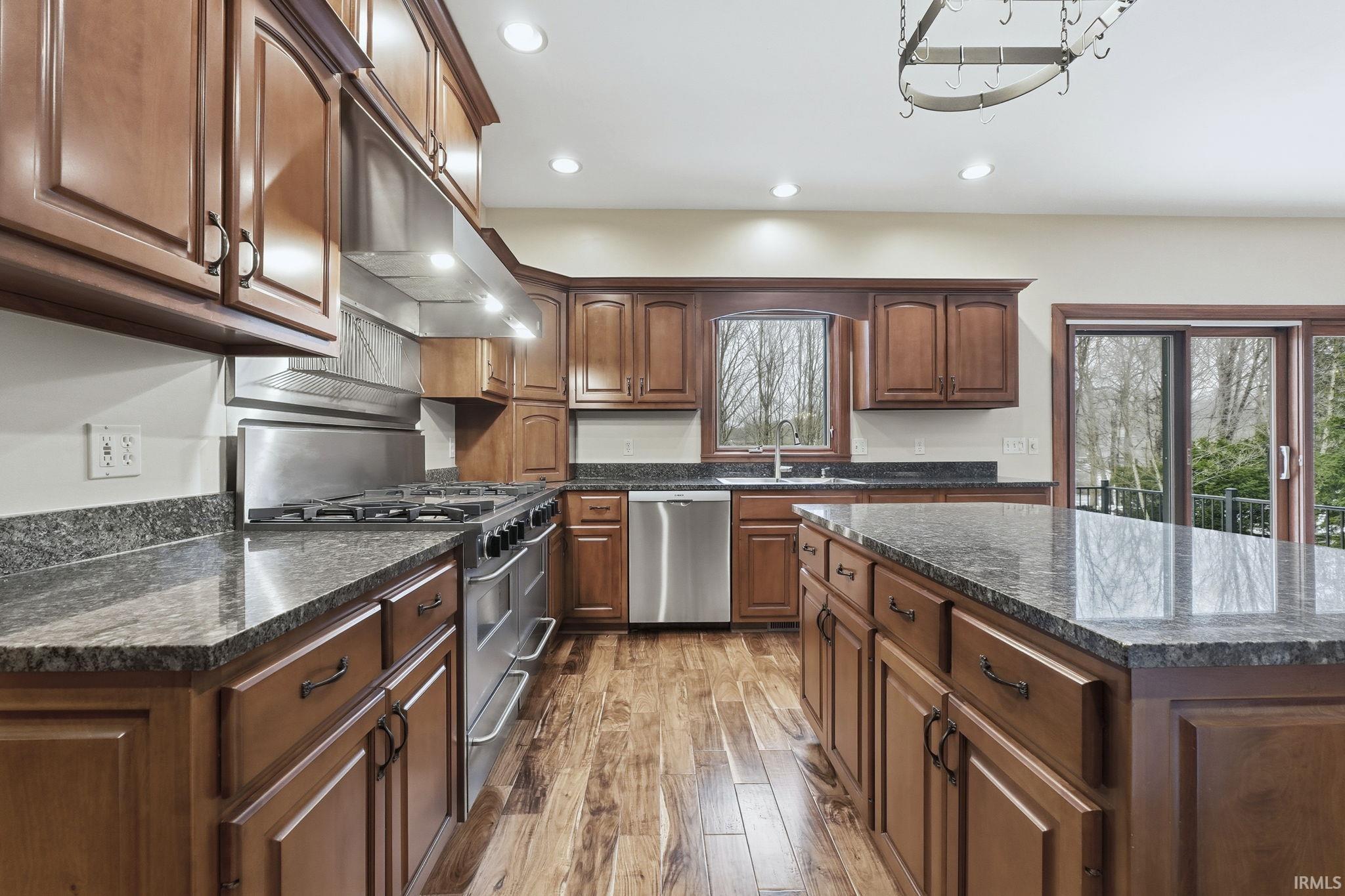 Kitchen stainless steel finishes, 5 STAR Gourmet Gas Range and  Double Ovens, overhead range hood, Cherry cabinetry, recessed lighting, and dark stone countertops