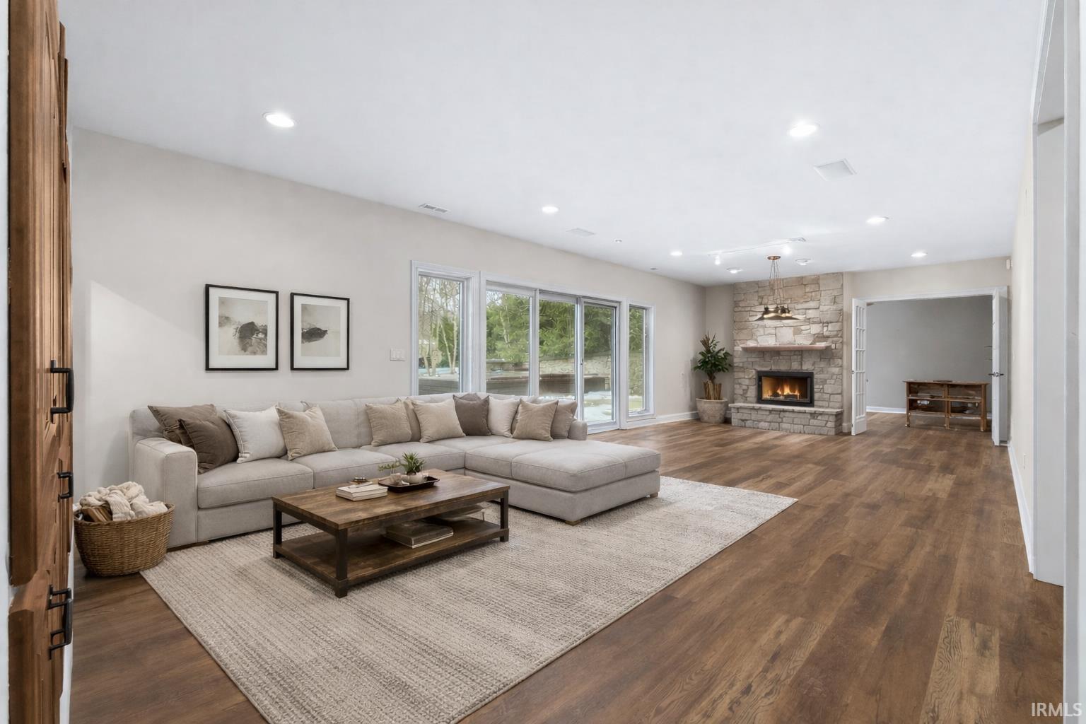 Living room featuring a stone fireplace, dark wood finished floors, and recessed lighting