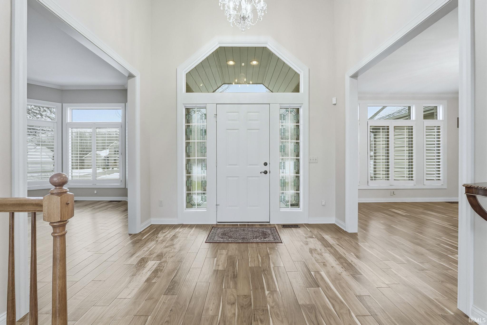 Foyer entrance with Engineered Hardwood (2019) span entire main level, a chandelier, a towering ceiling, healthy amount of natural light, and ornamental molding