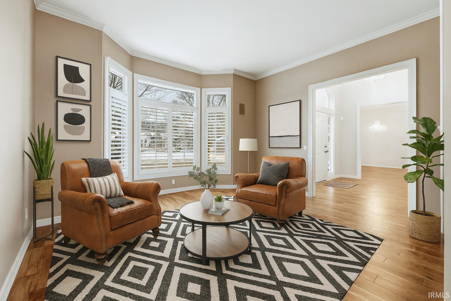Virtually Staged- Living area with ornamental molding and light wood finished floors