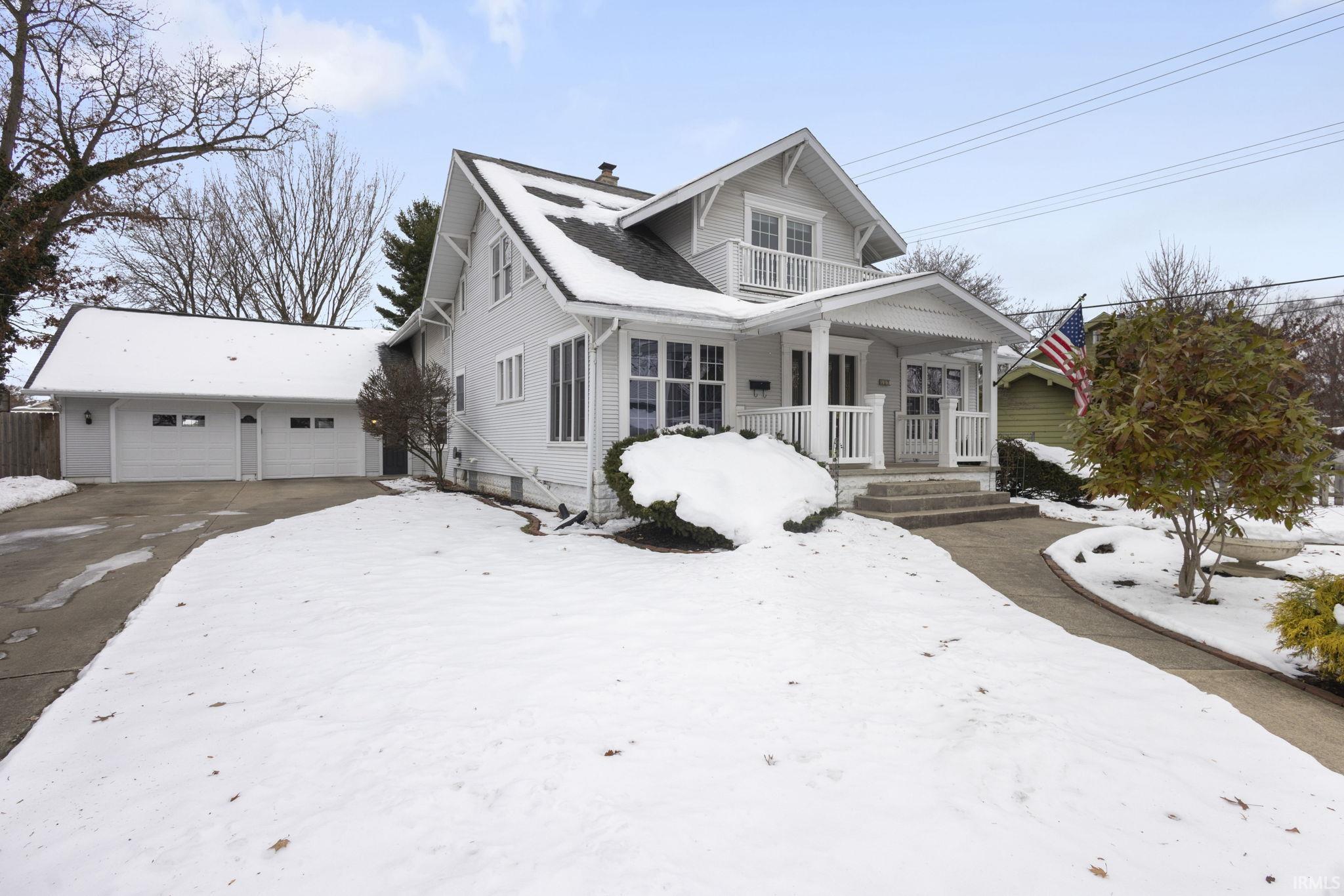 View of front of property featuring a garage, covered porch, a chimney, and driveway
