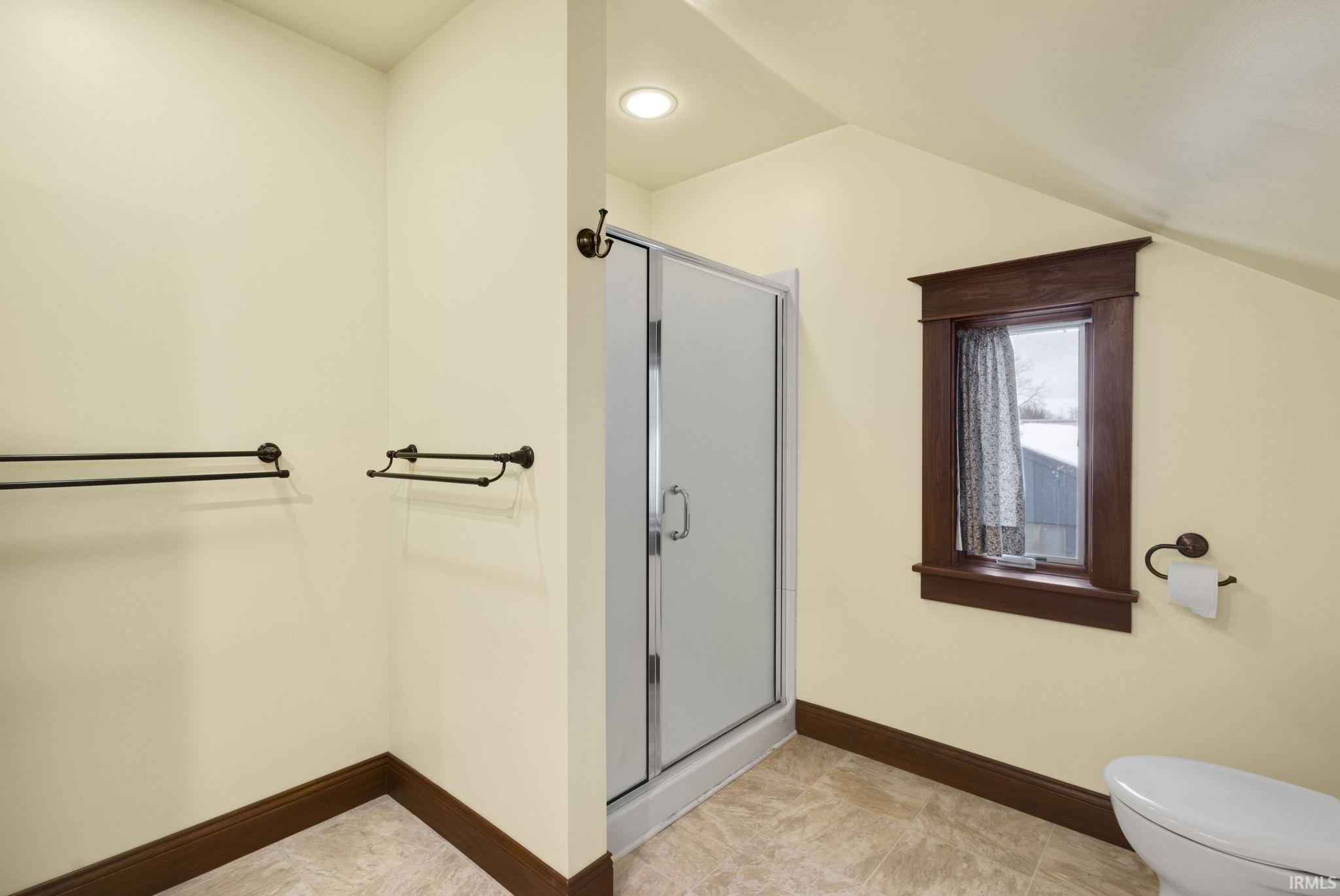 Bathroom featuring a shower stall and lofted ceiling