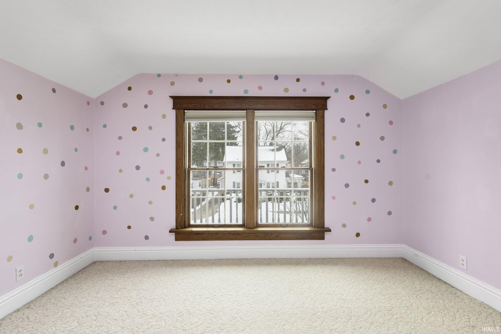 Spare room with vaulted ceiling, light colored carpet, and wallpapered walls