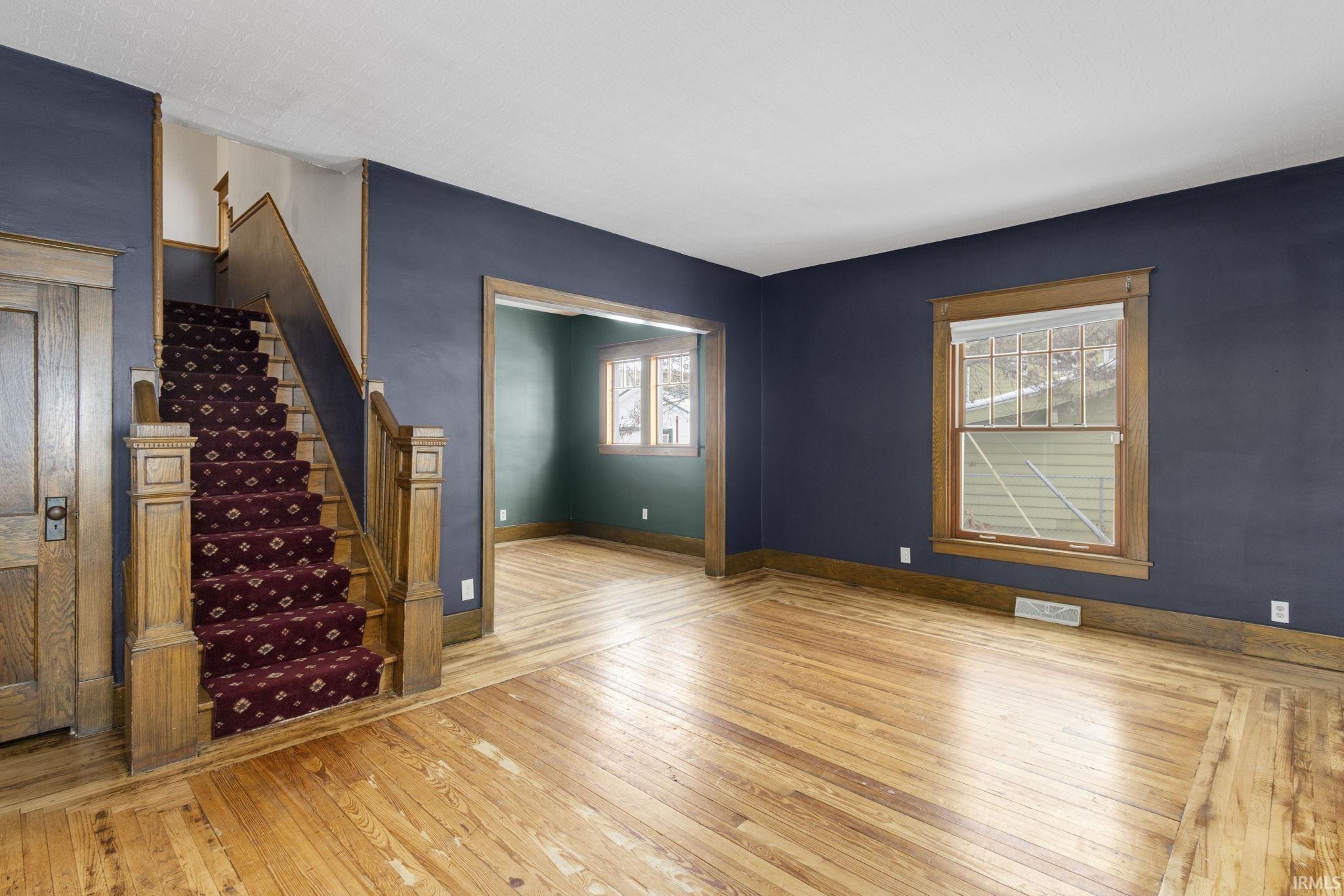 Unfurnished living room featuring light wood-type flooring and stairs