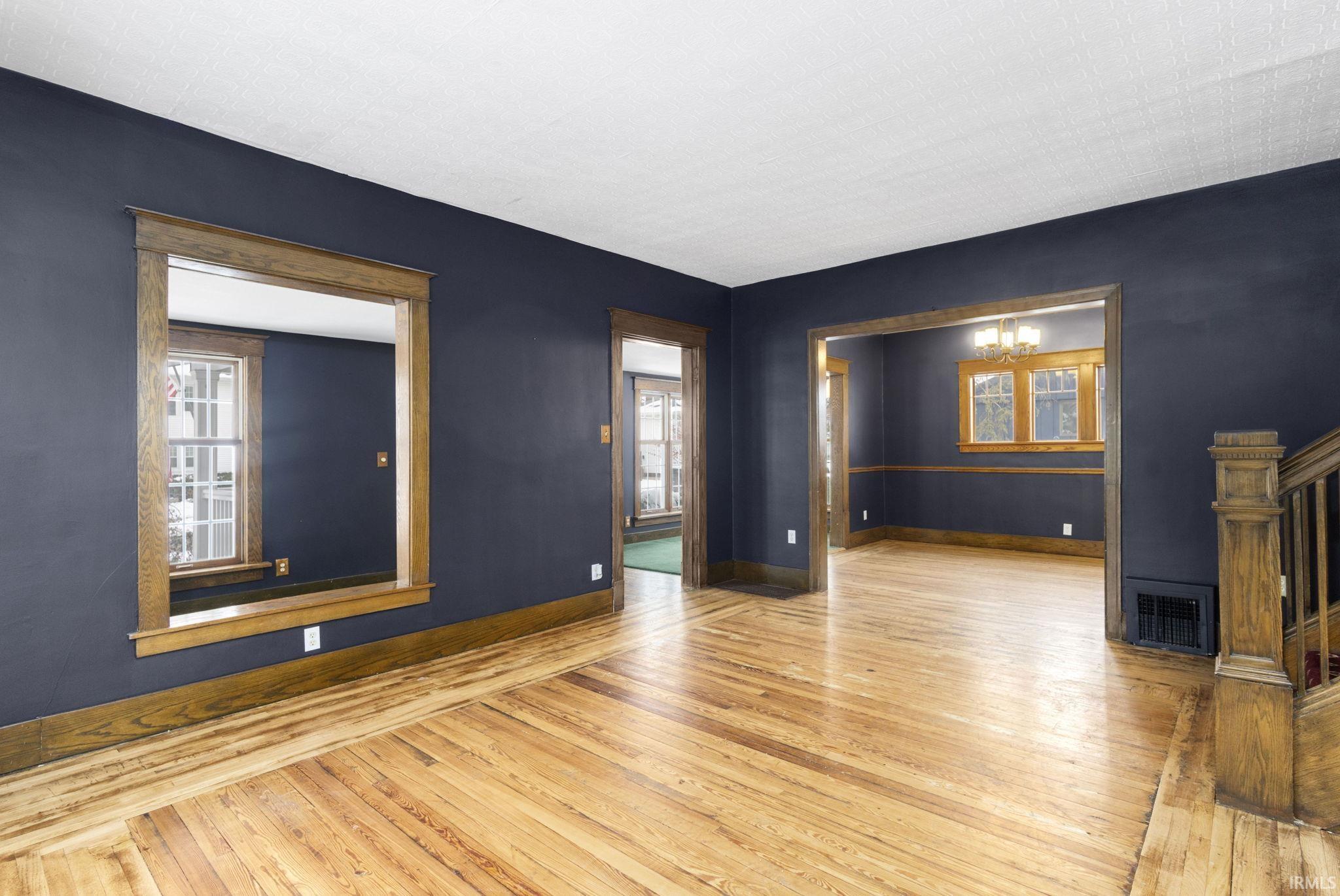 Unfurnished living room with hardwood / wood-style floors, a chandelier, healthy amount of natural light, and stairs