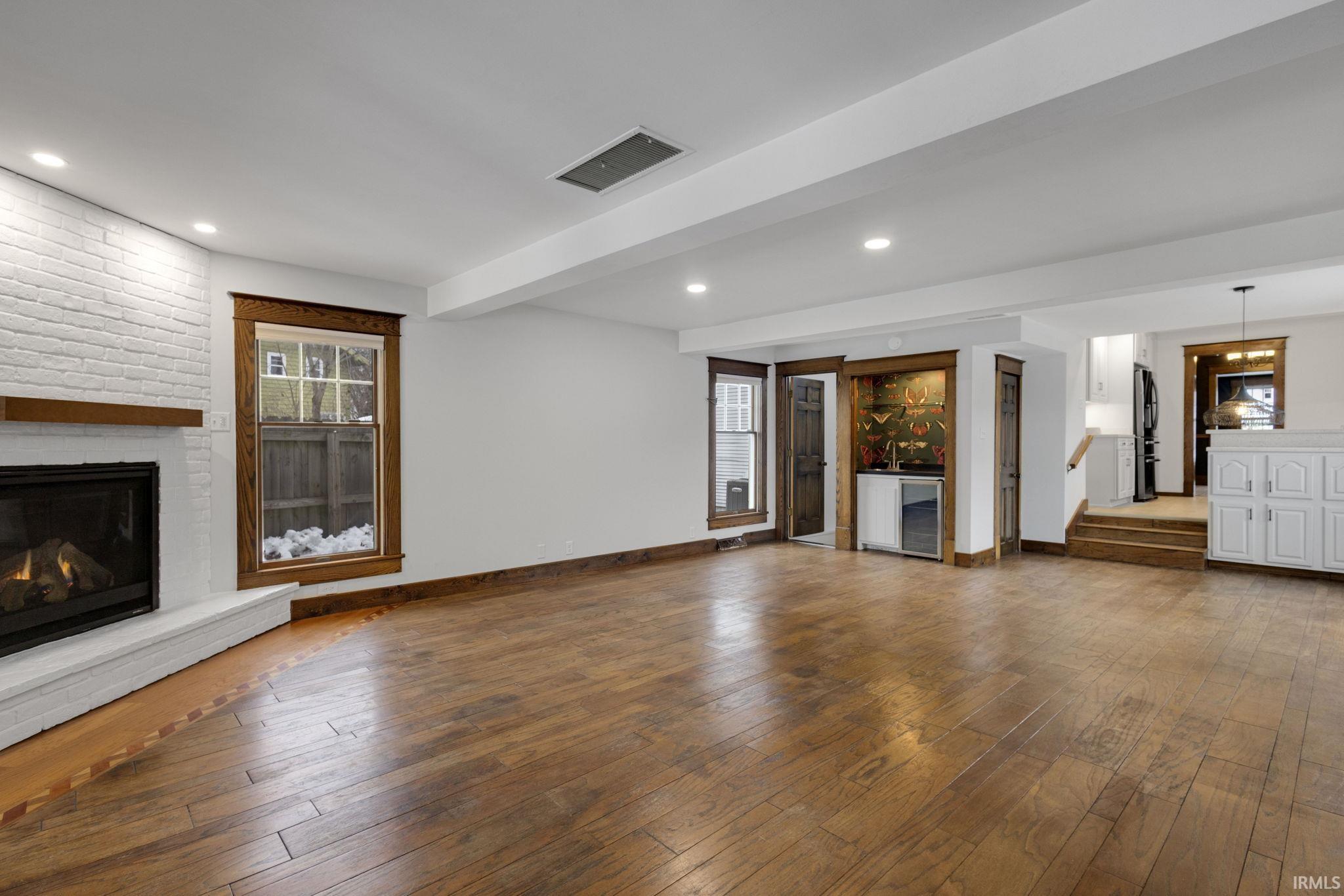 Unfurnished living room with hardwood / wood-style flooring, a fireplace, beverage cooler, recessed lighting, and plenty of natural light
