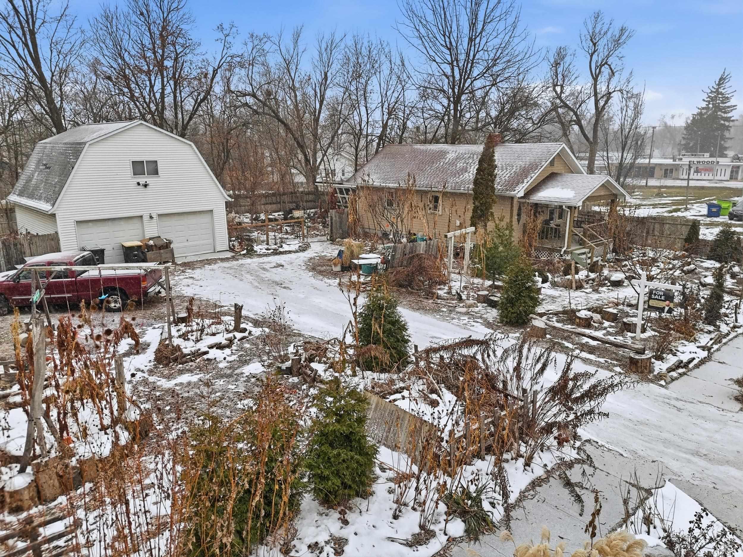 Yard layered in snow featuring an outdoor structure and a detached garage