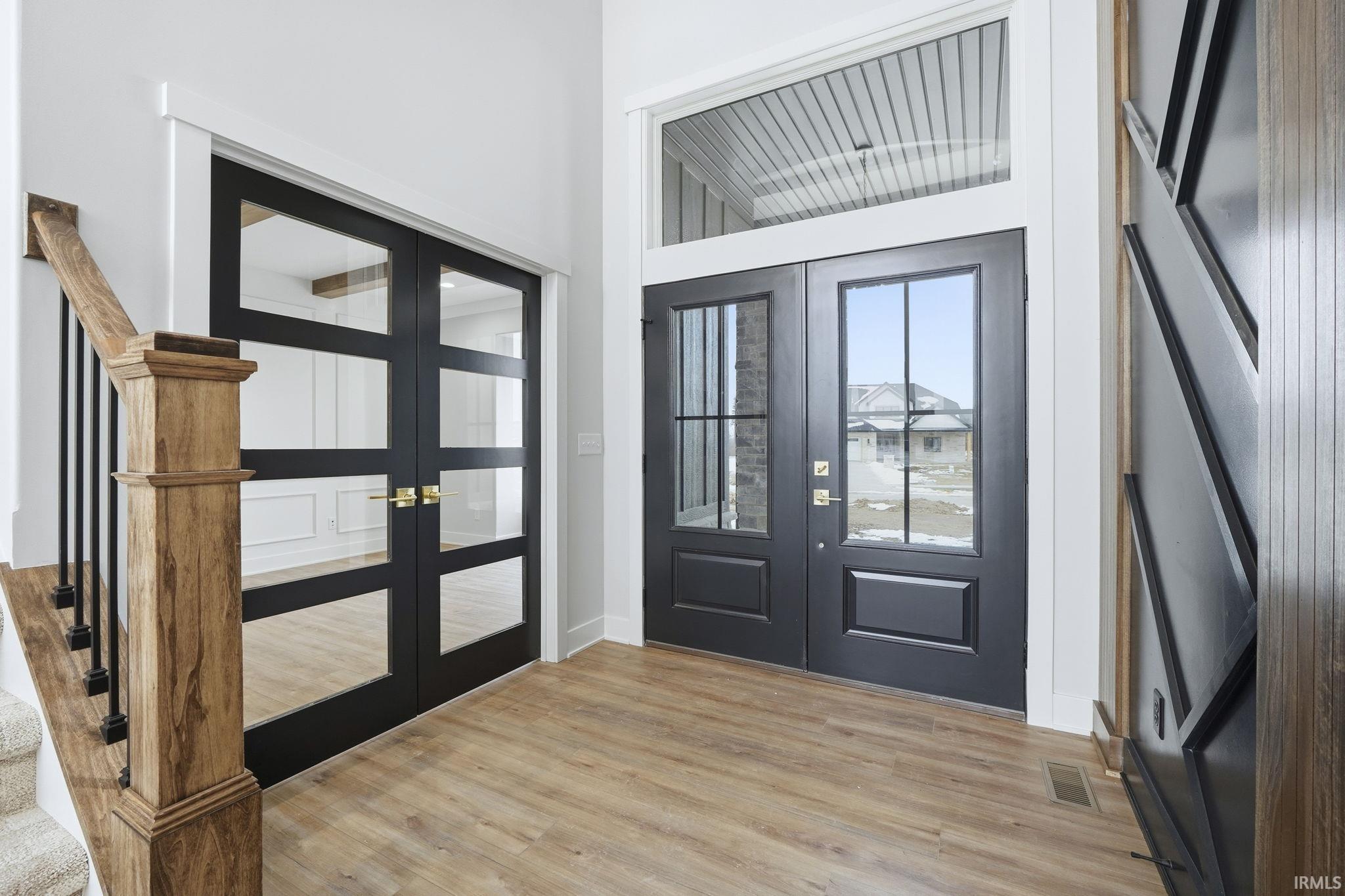 Foyer entrance featuring french doors, stairway, and light wood-style floors