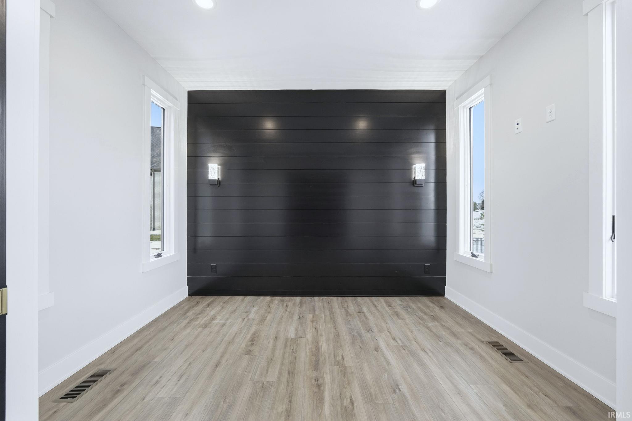 Corridor featuring light wood finished floors, an accent wall, and recessed lighting
