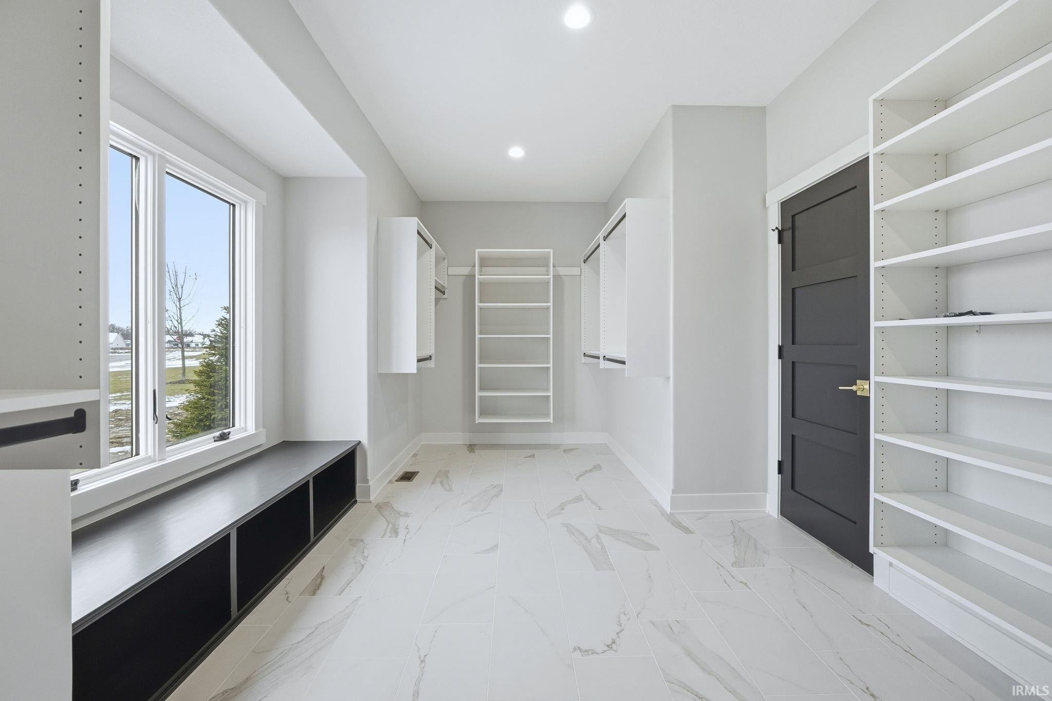 Walk in closet featuring light marble finish flooring