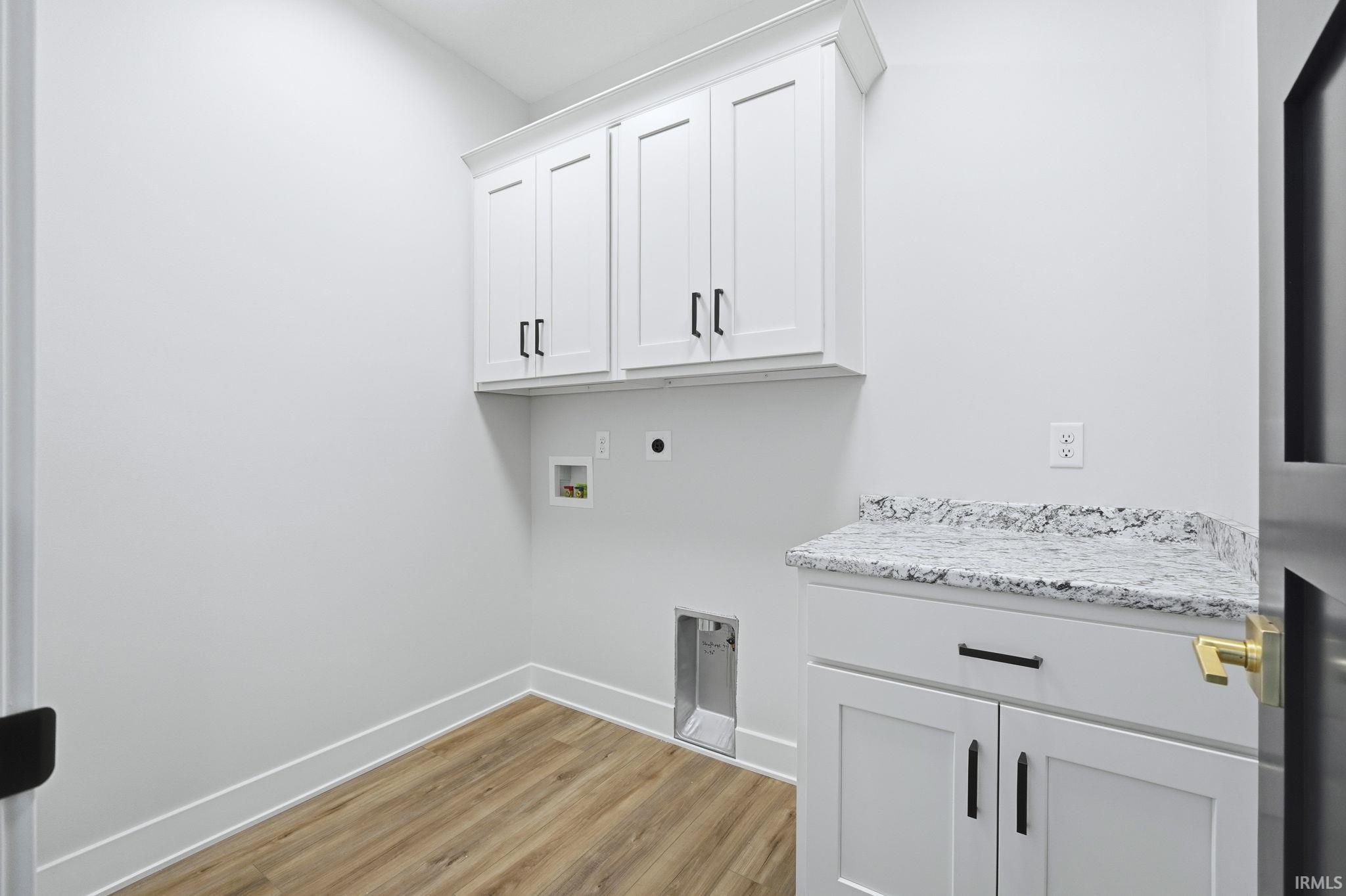 Laundry area with electric dryer hookup, washer hookup, light wood finished floors, and cabinet space