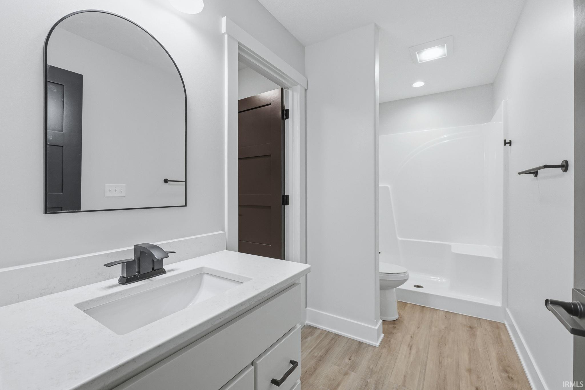 Full bathroom featuring vanity, a shower stall, and light wood finished floors