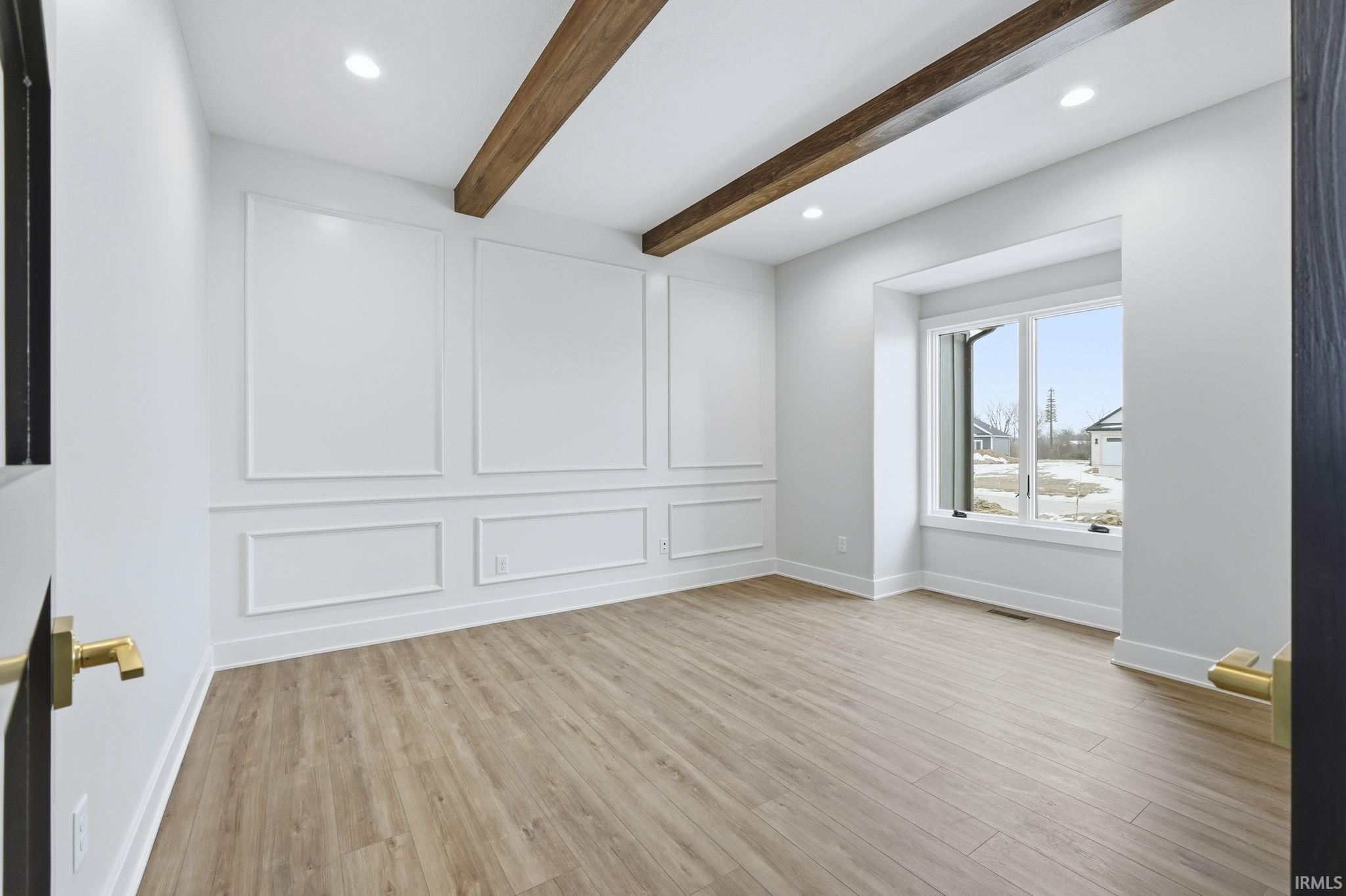 Spare room with light wood-style flooring, recessed lighting, beam ceiling, and a decorative wall