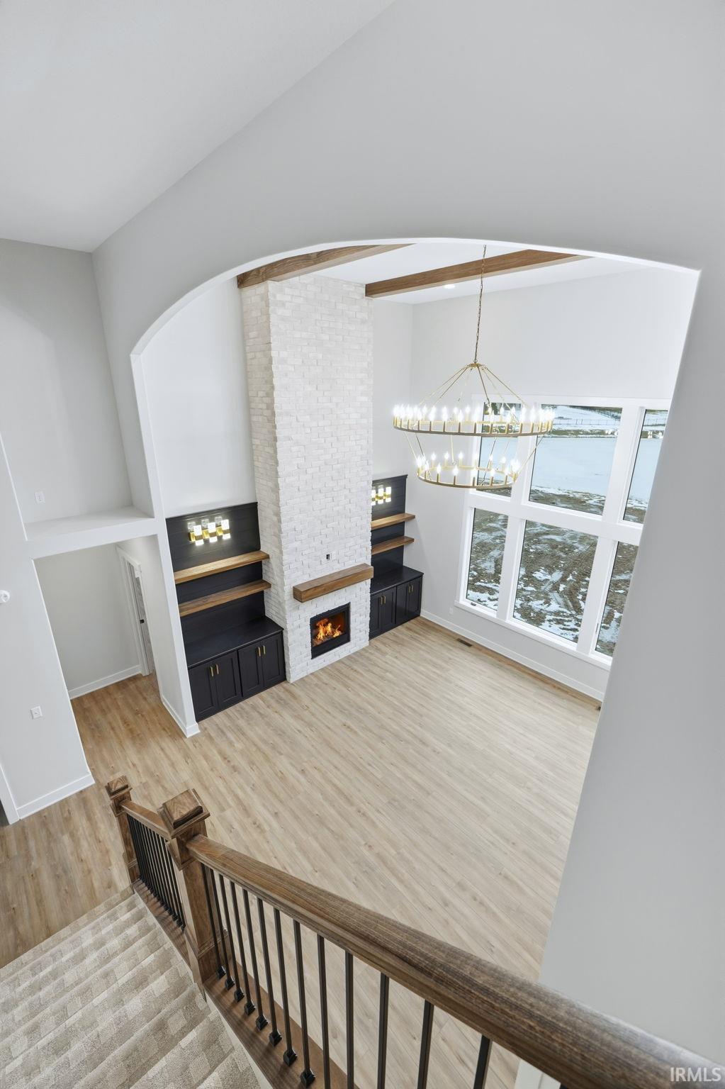 Stairs featuring a large fireplace, wood finished floors, and a chandelier