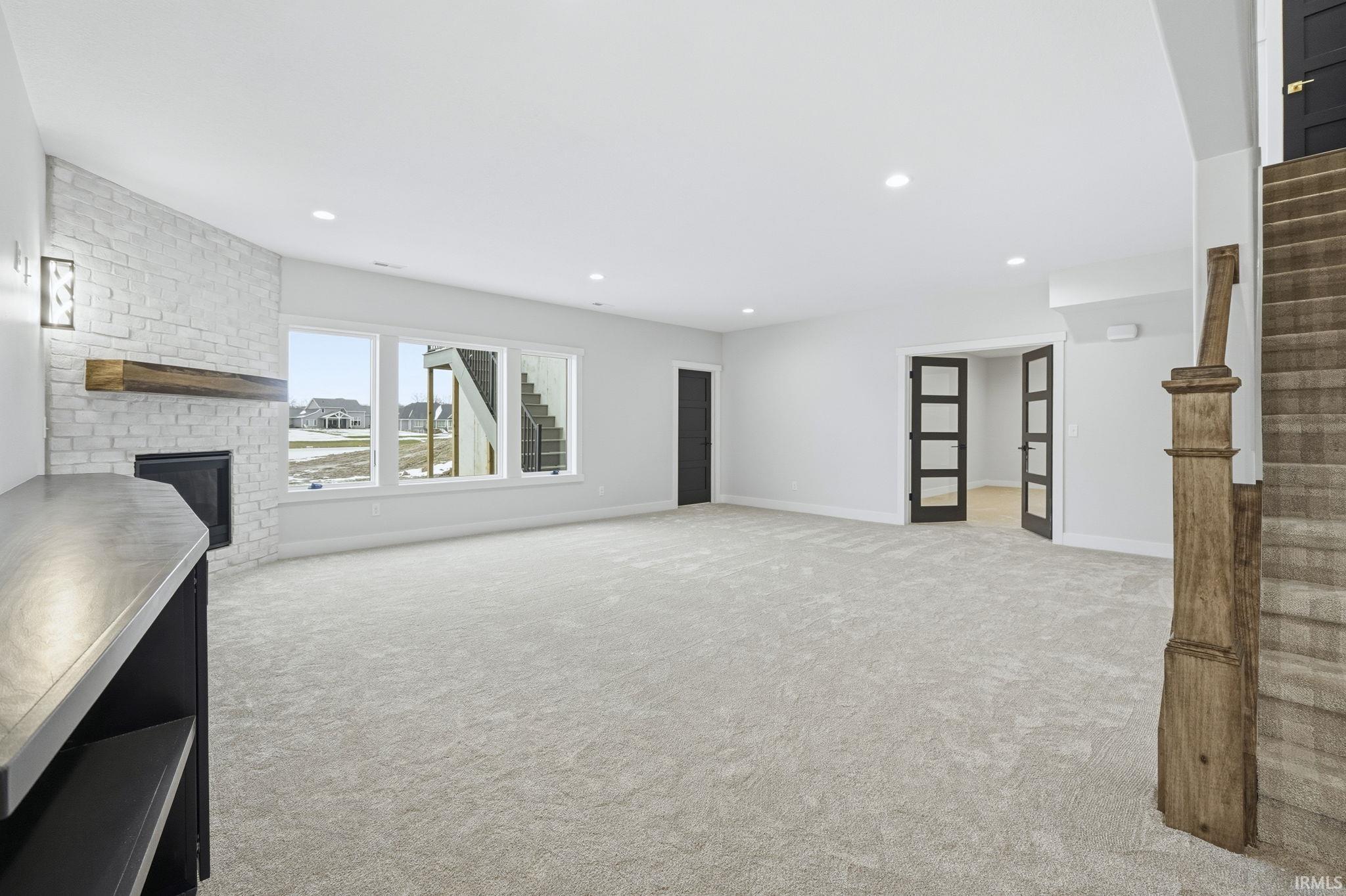Unfurnished living room featuring stairs, a fireplace, light carpet, and recessed lighting