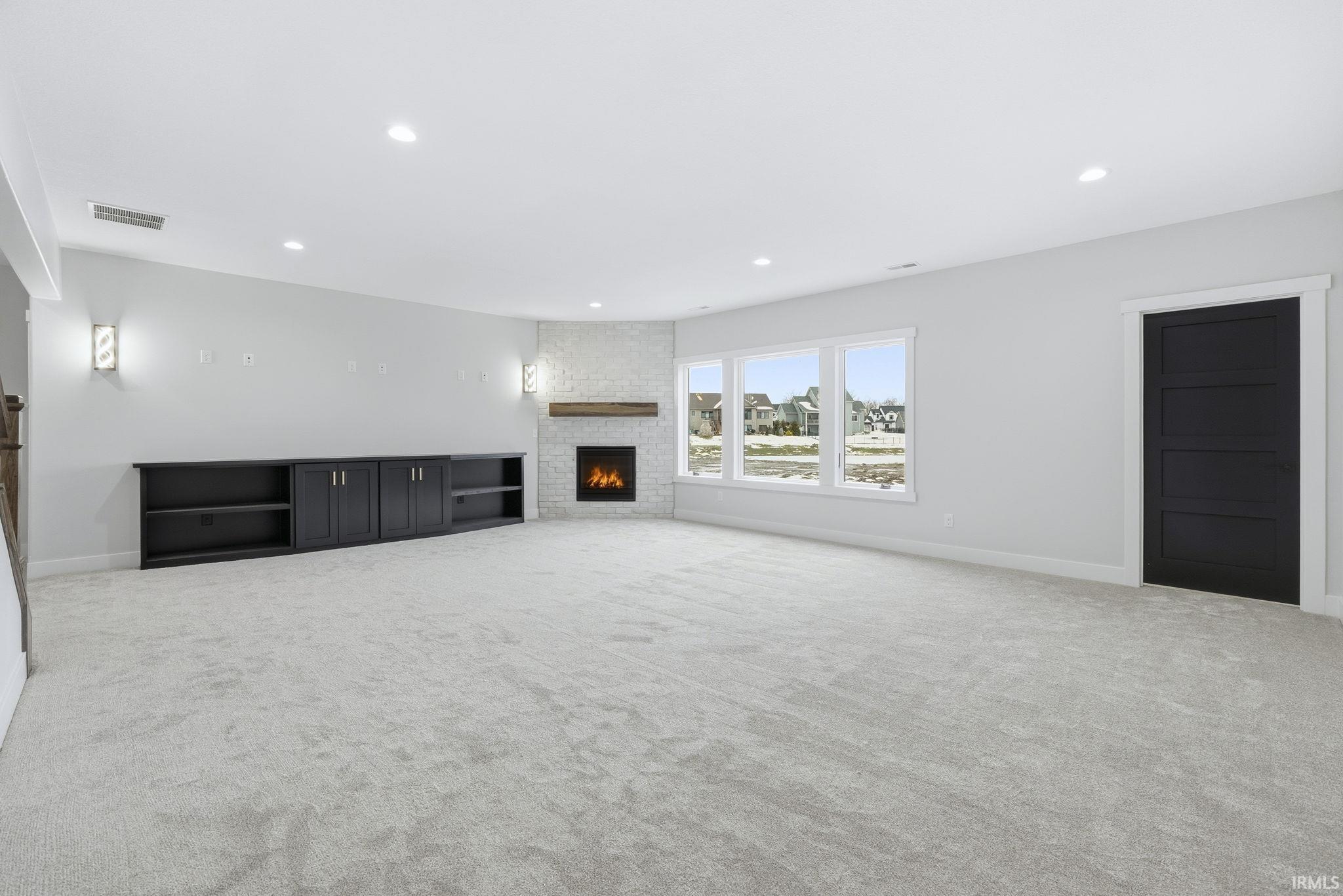 Unfurnished living room featuring a fireplace, recessed lighting, and light colored carpet