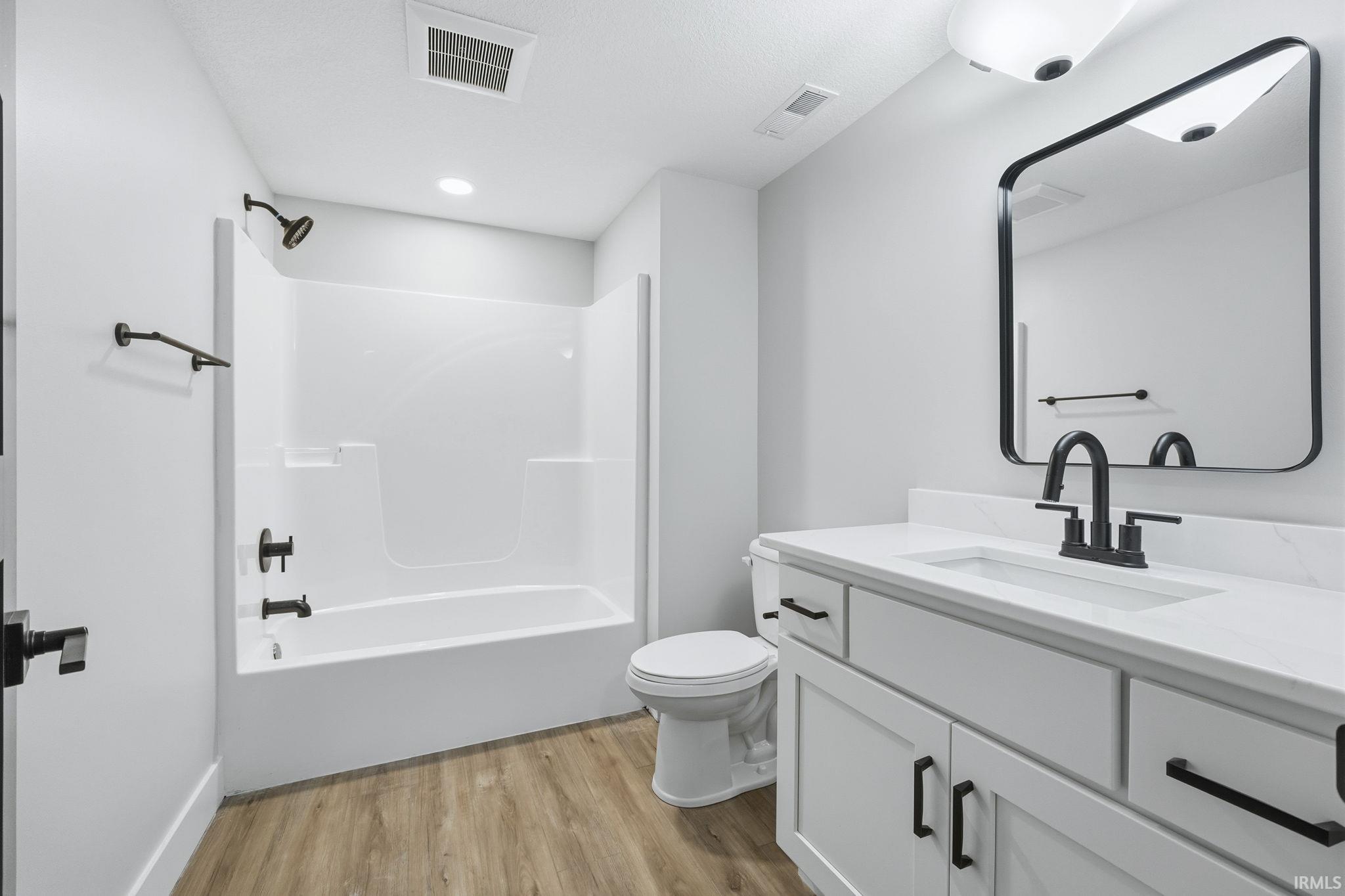 Bathroom with vanity, bathing tub / shower combination, and light wood-style floors