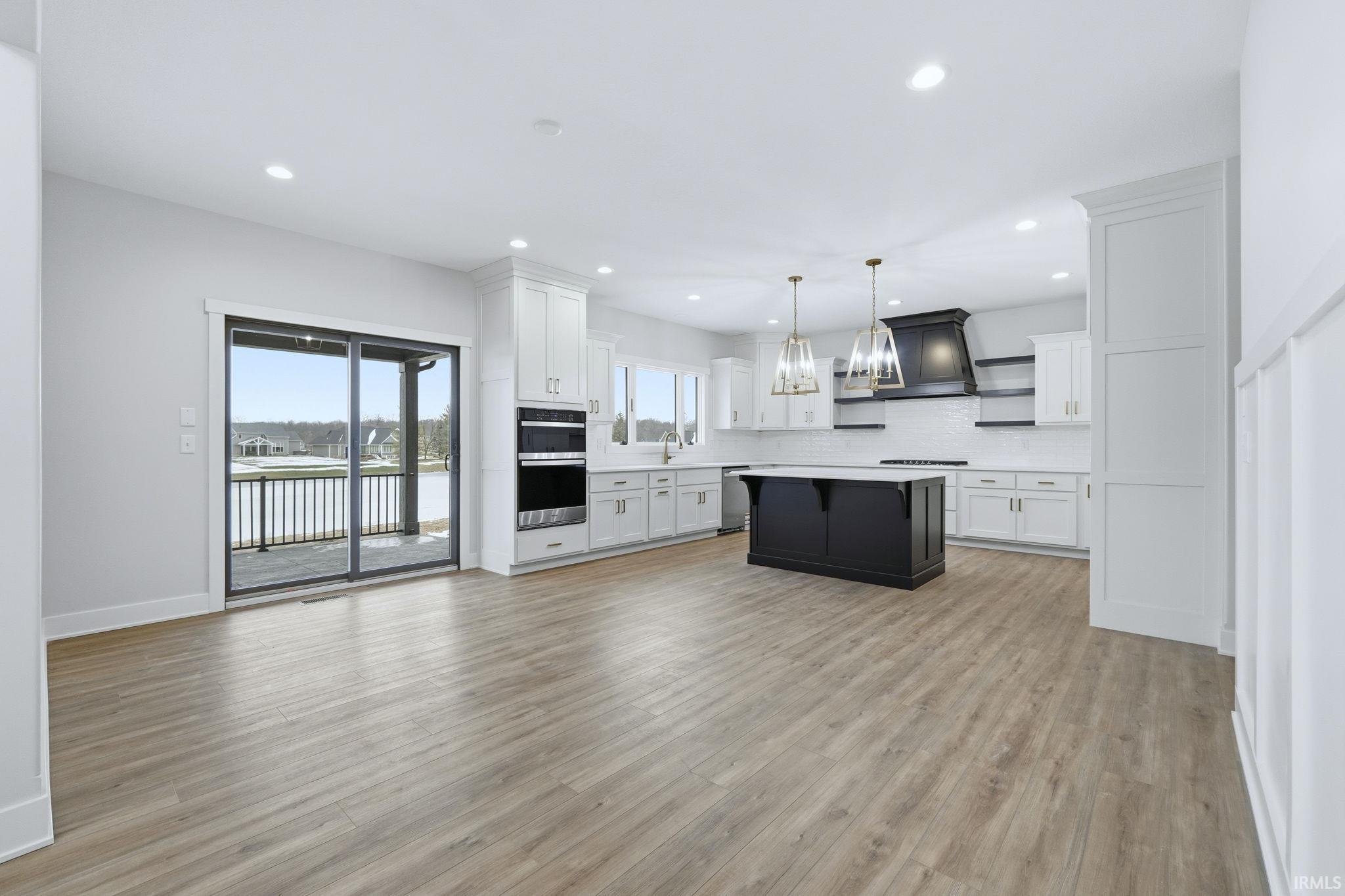 Kitchen with white cabinetry, decorative light fixtures, backsplash, light wood-style flooring, and recessed lighting
