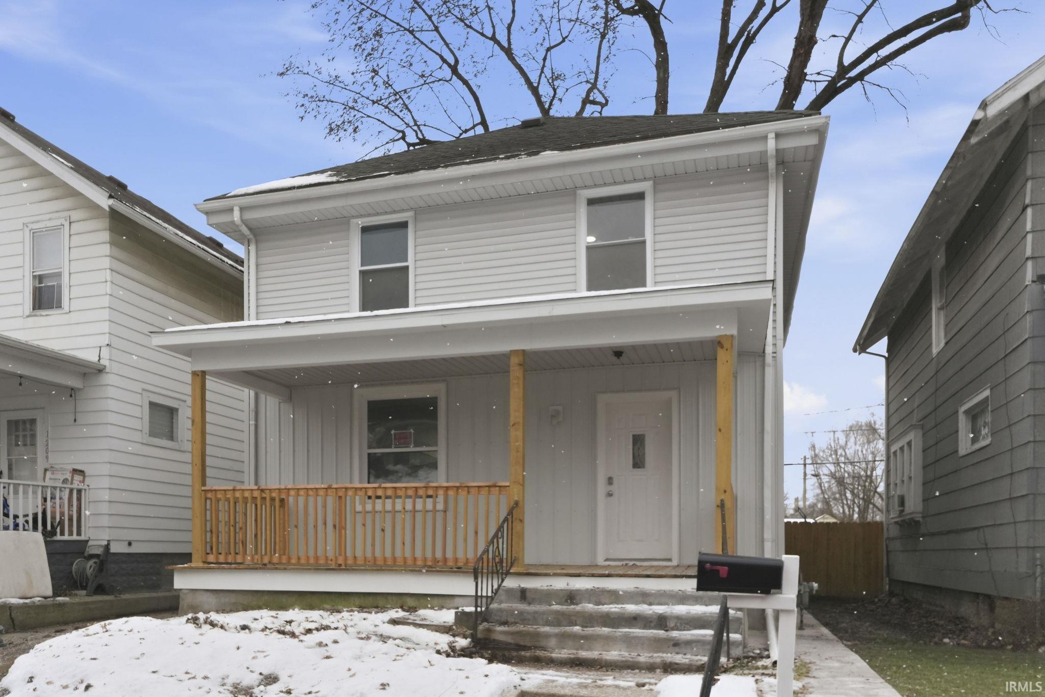 Traditional style home with board and batten siding, covered porch, and roof with shingles