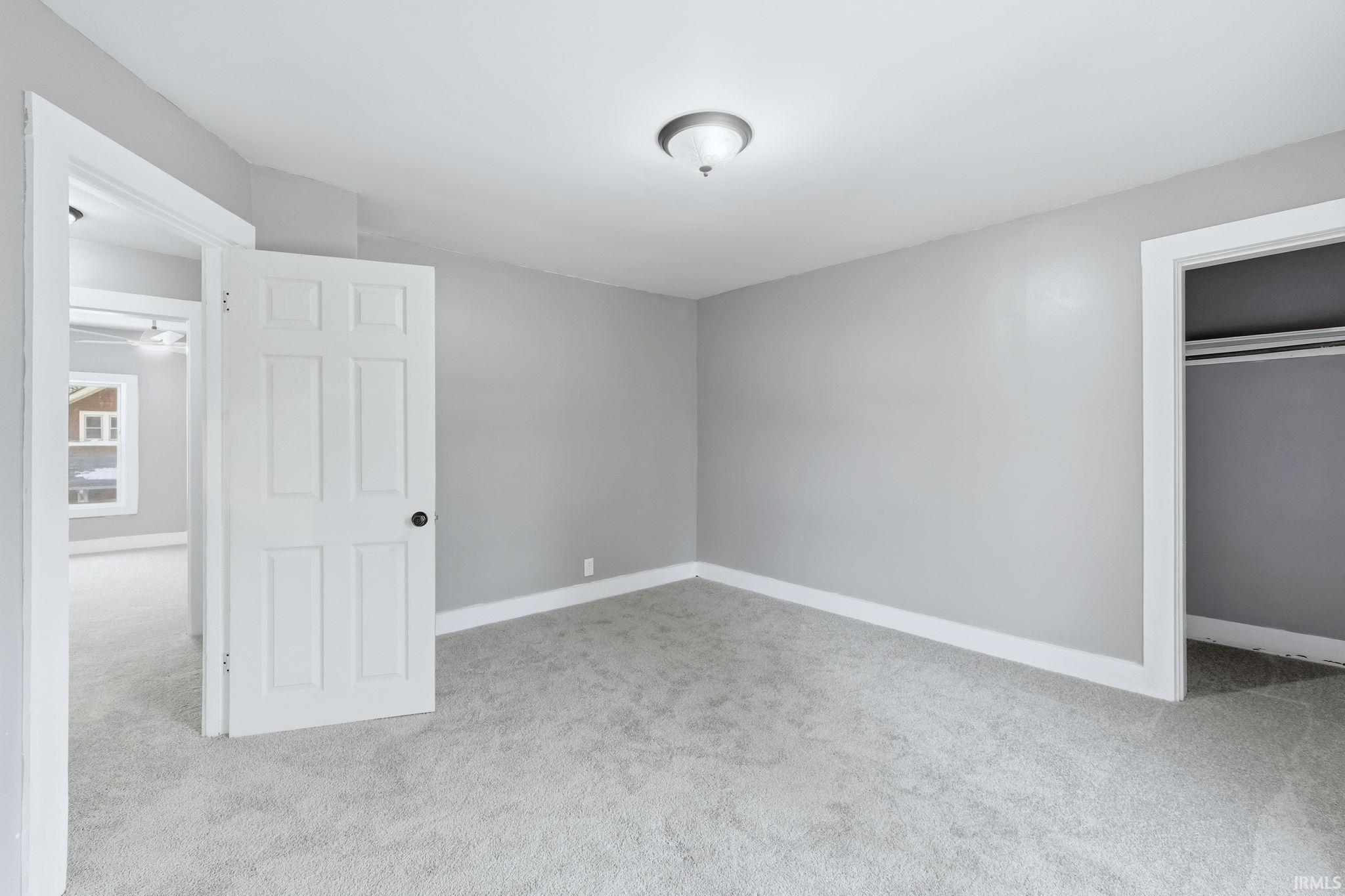 Unfurnished bedroom with light carpet and a closet