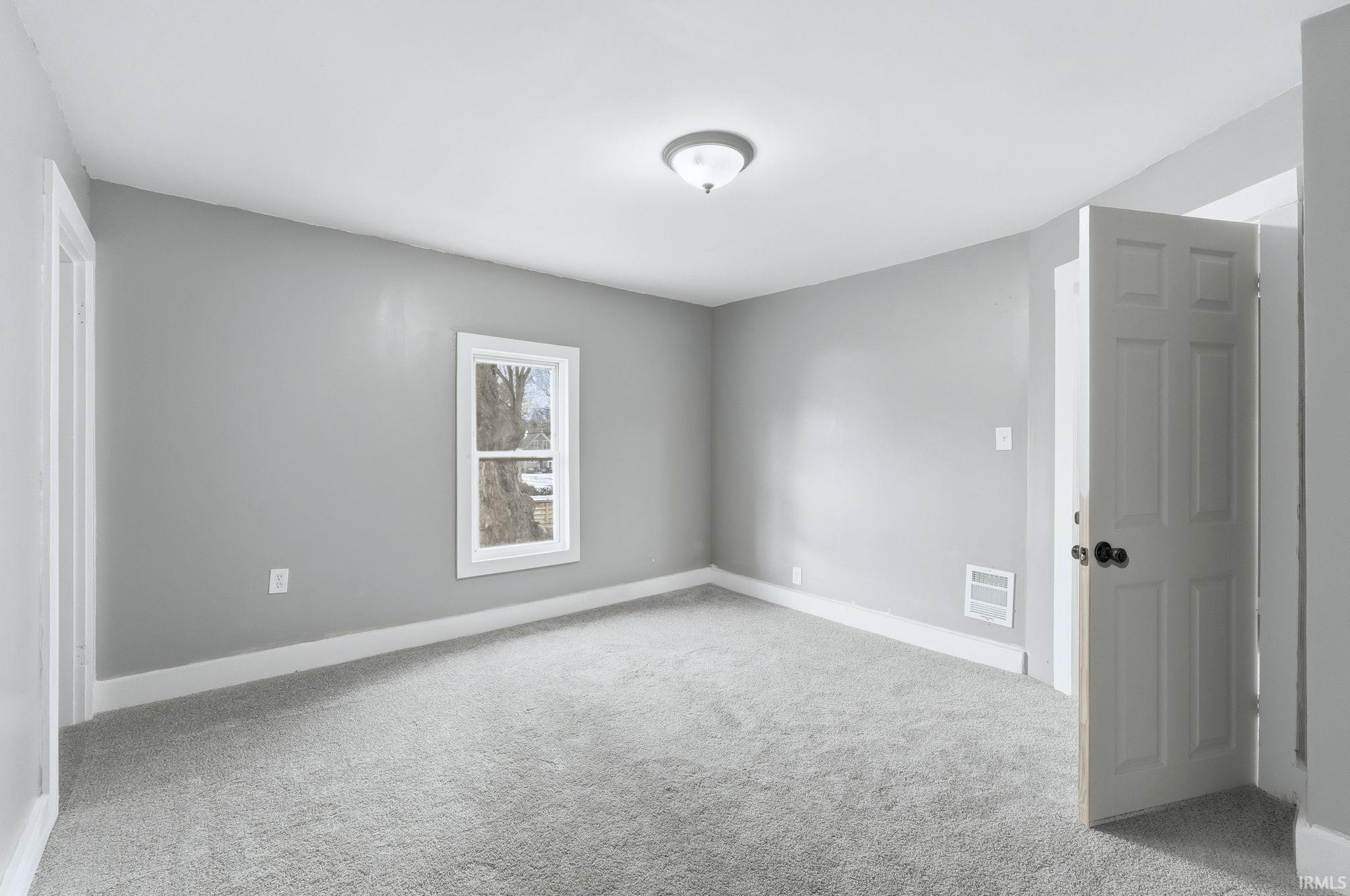 Spare room featuring light carpet and baseboards