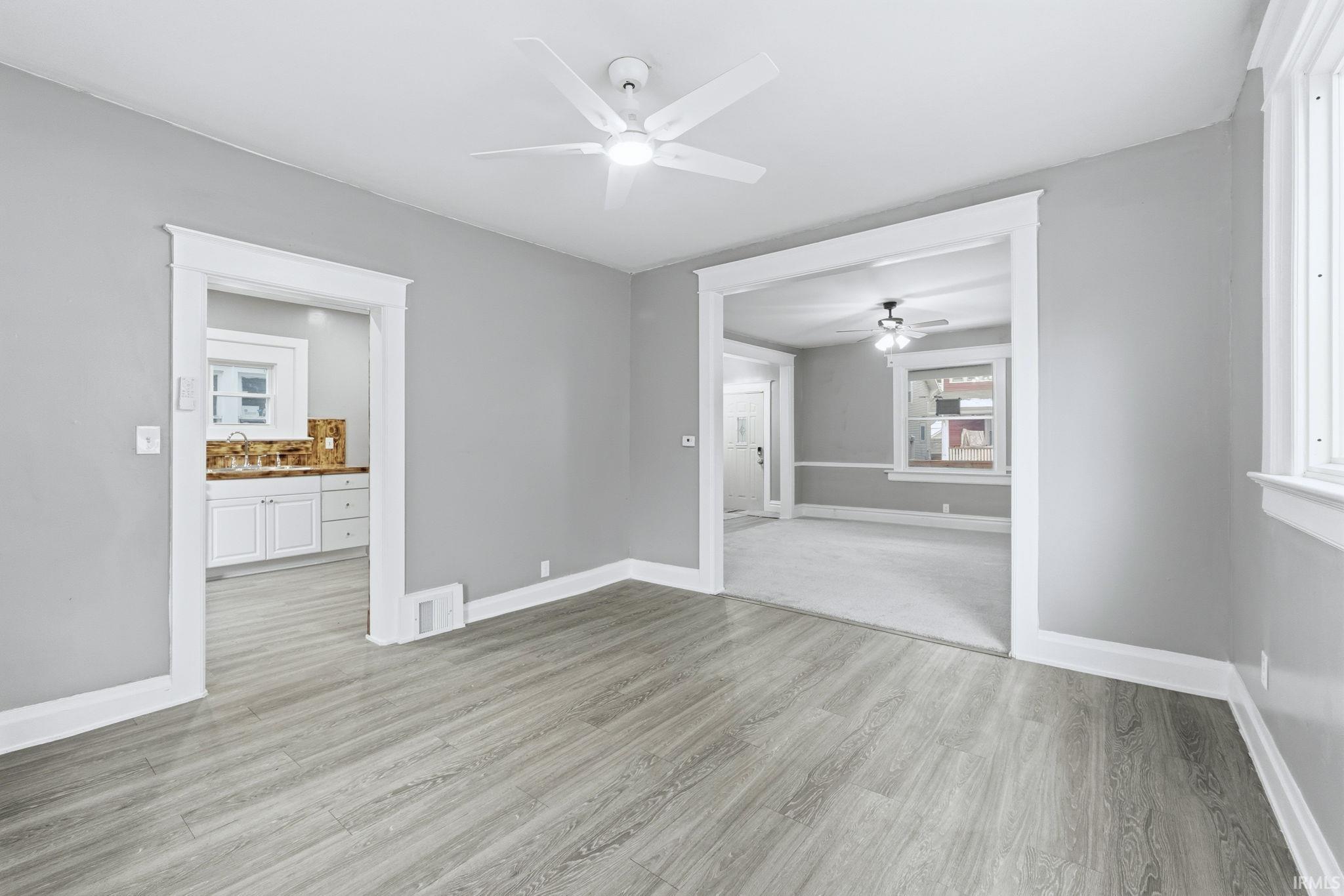 Unfurnished living room featuring light wood-style floors and a ceiling fan