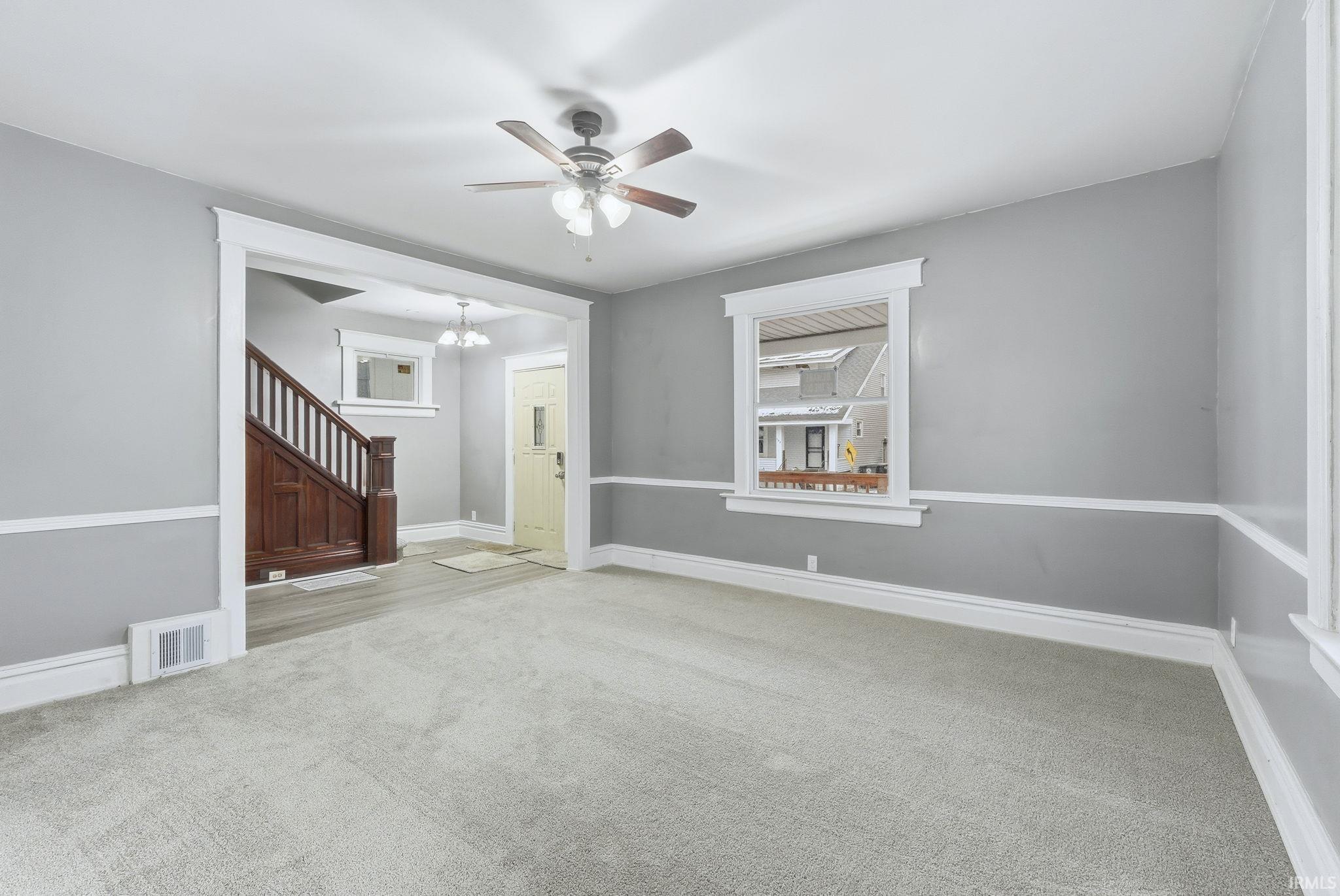 Spare room featuring ceiling fan, carpet floors, and a chandelier