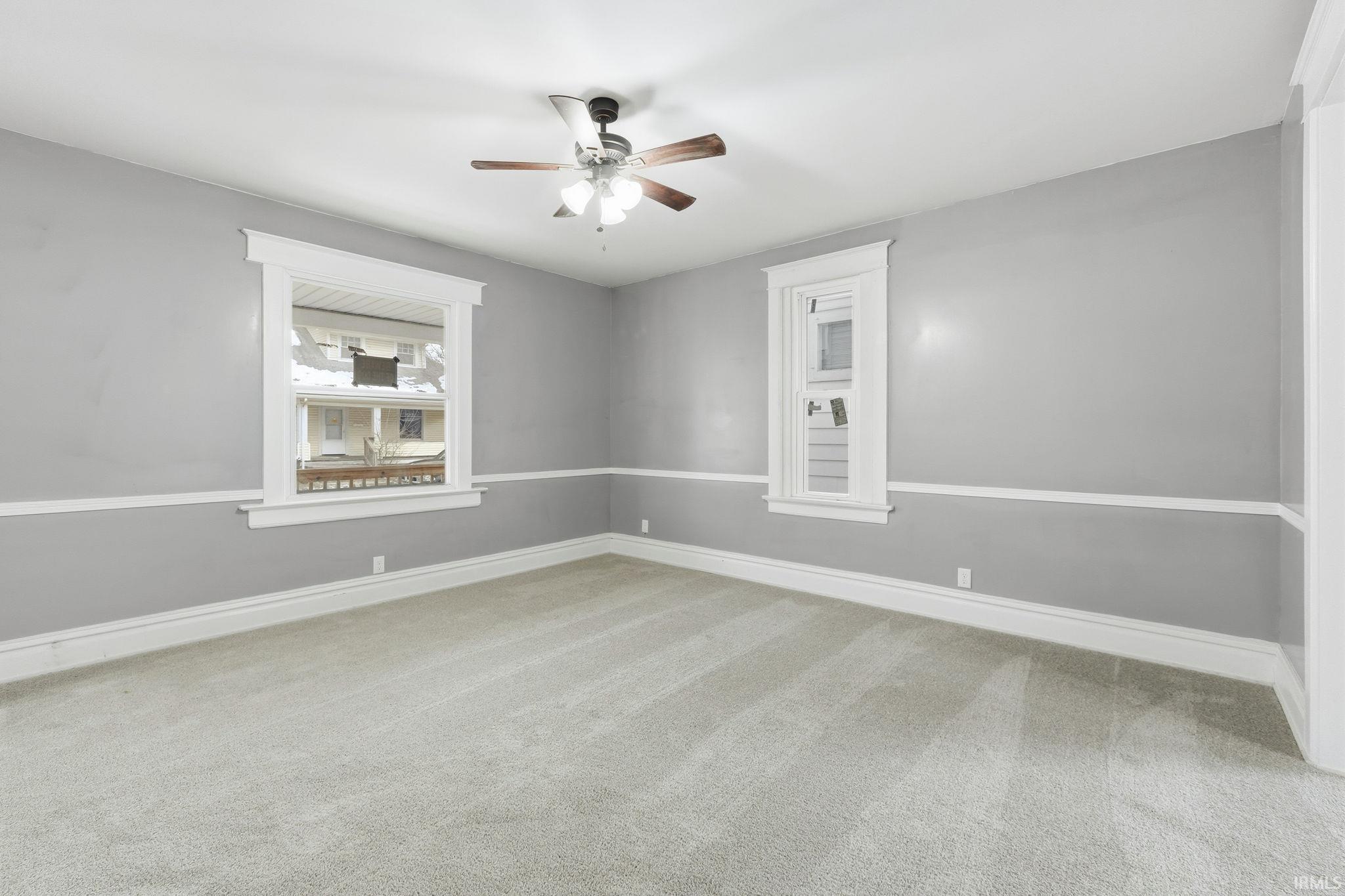 Empty room with light colored carpet and a ceiling fan