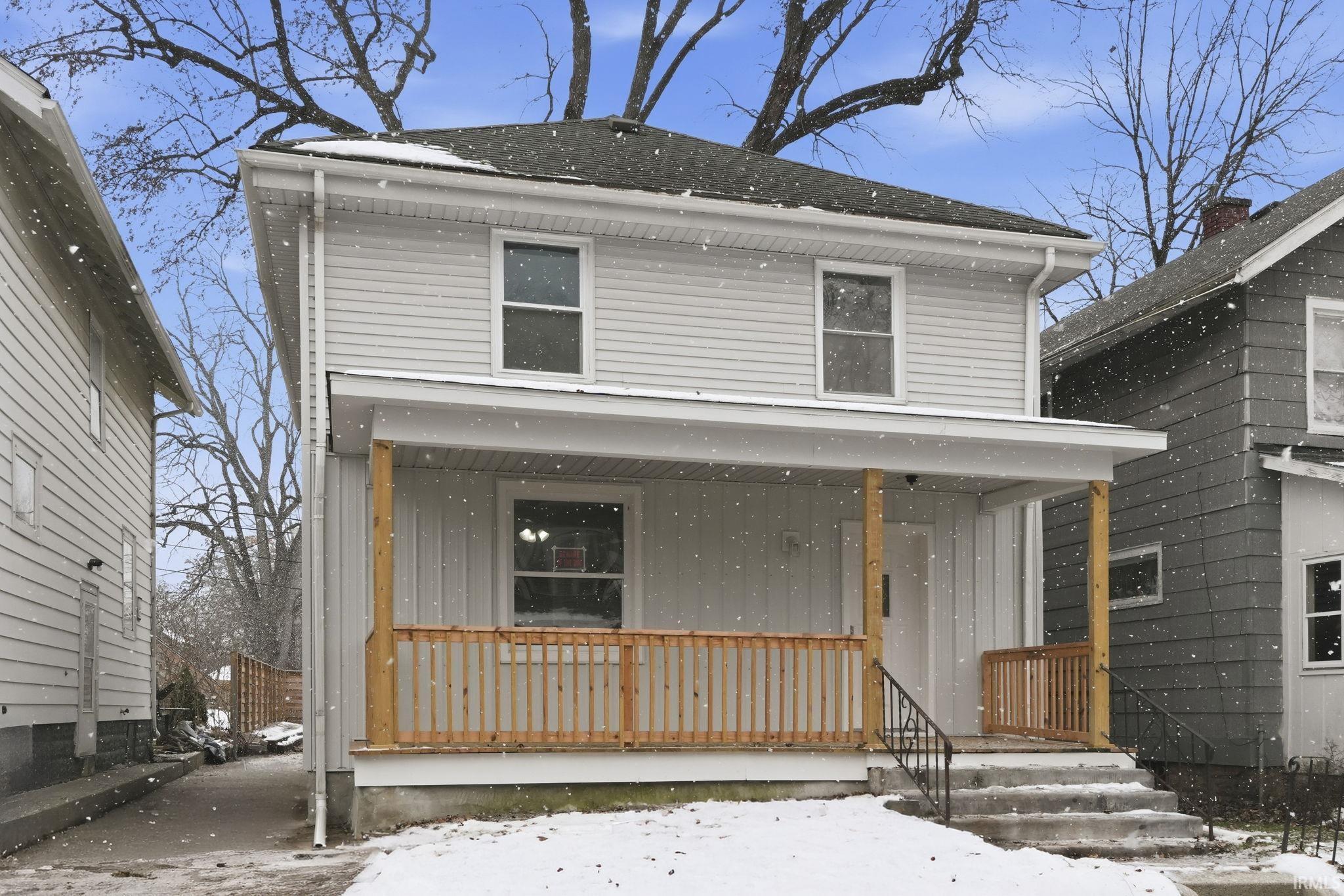 American foursquare style home featuring a porch, board and batten siding, and roof with shingles