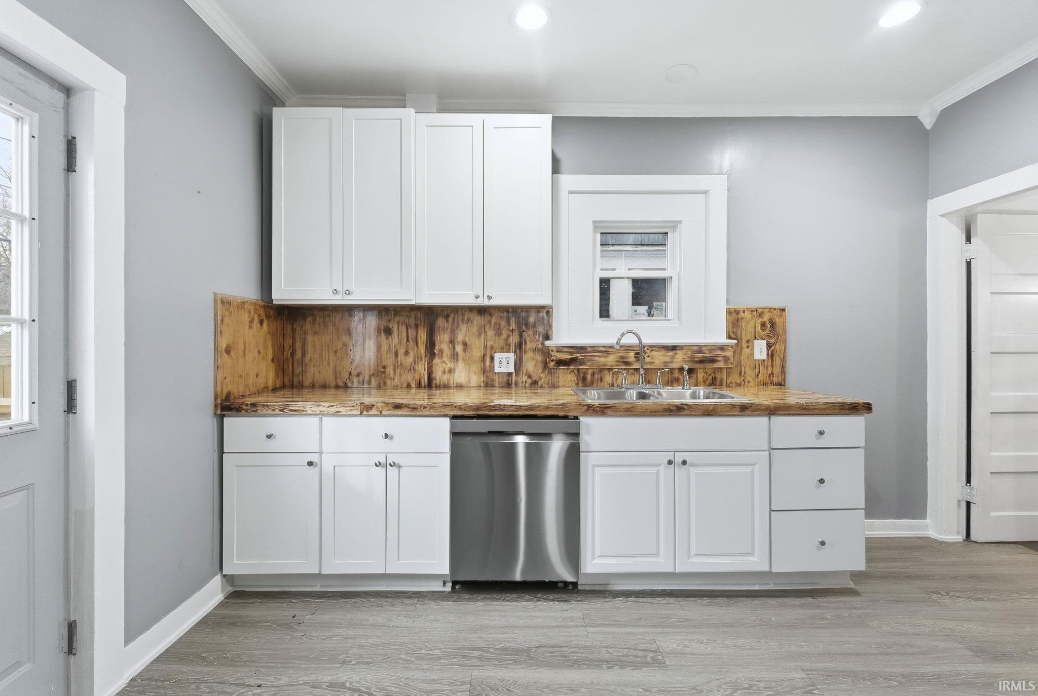 Kitchen with white cabinetry, crown molding, dishwasher, tasteful backsplash, and recessed lighting