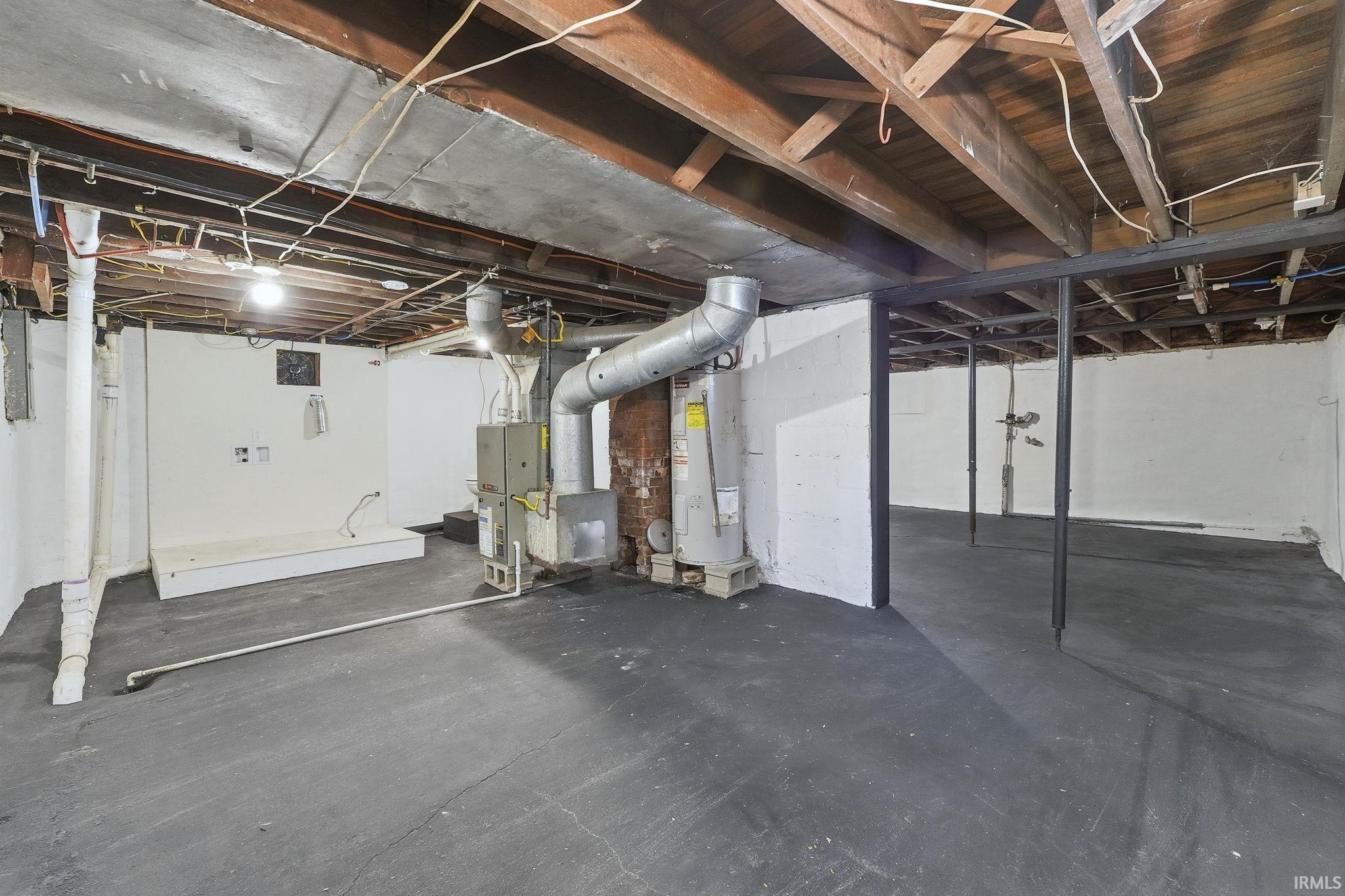 Unfinished basement featuring electric water heater and heating unit