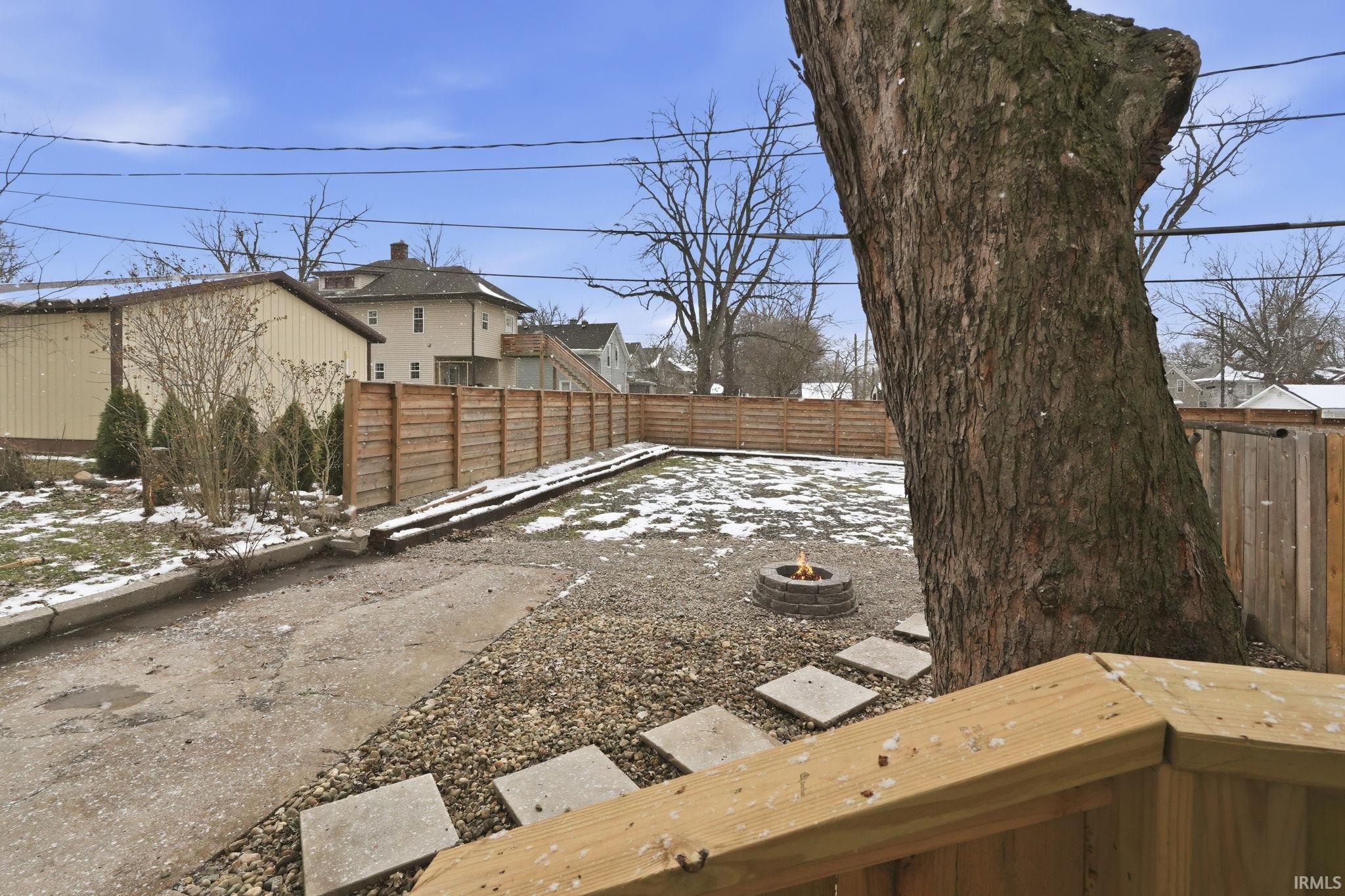 Snowy yard with a fire pit and a fenced backyard
