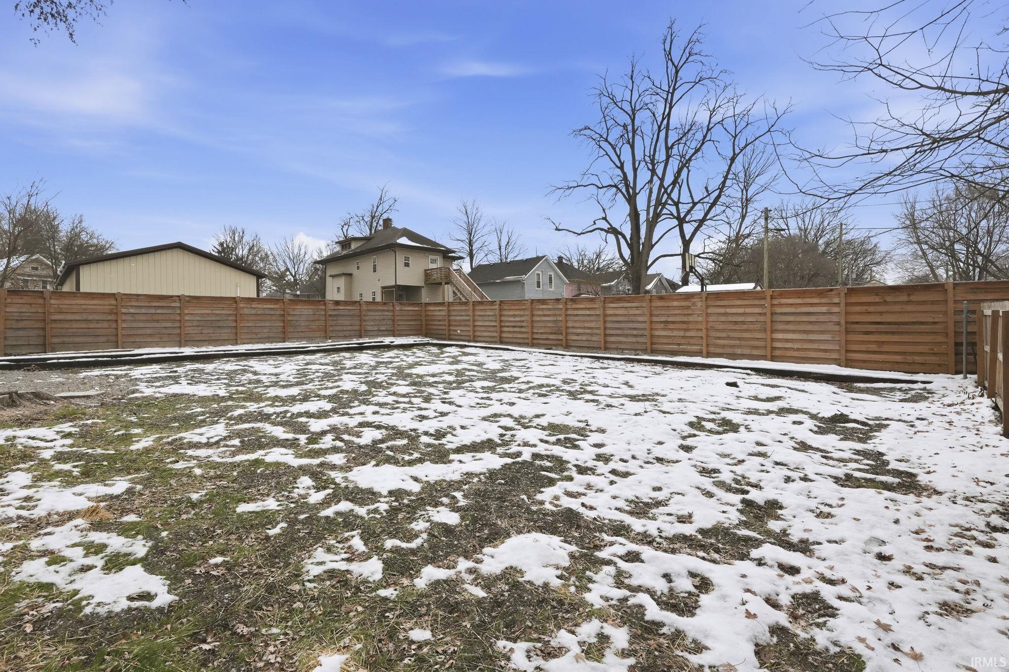 Yard layered in snow with a fenced backyard