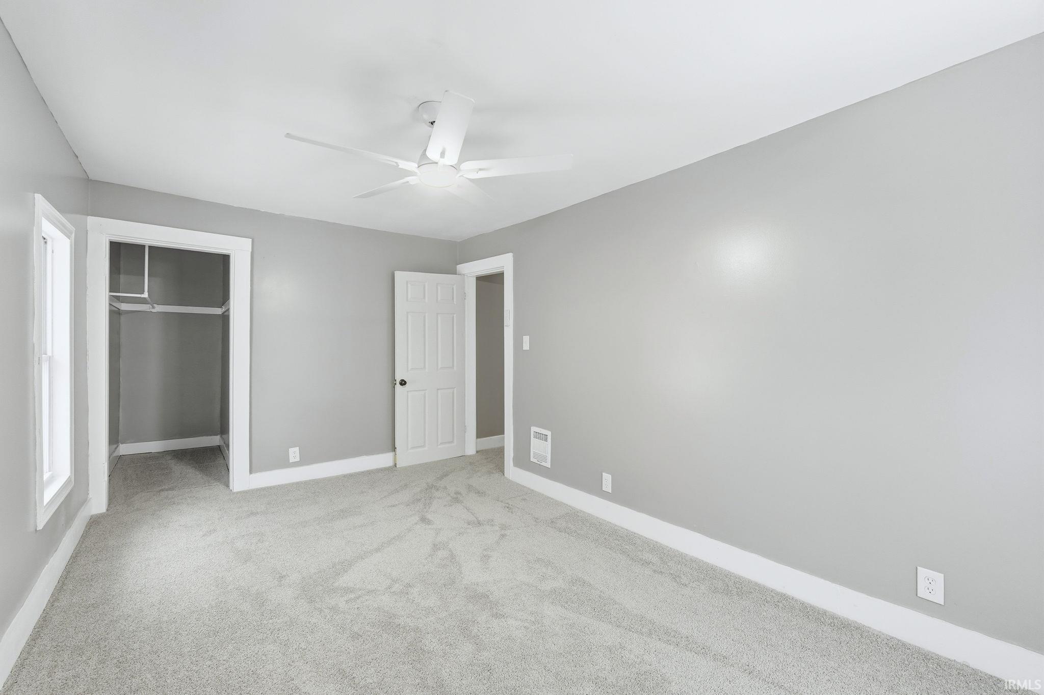 Unfurnished bedroom featuring light colored carpet and ceiling fan