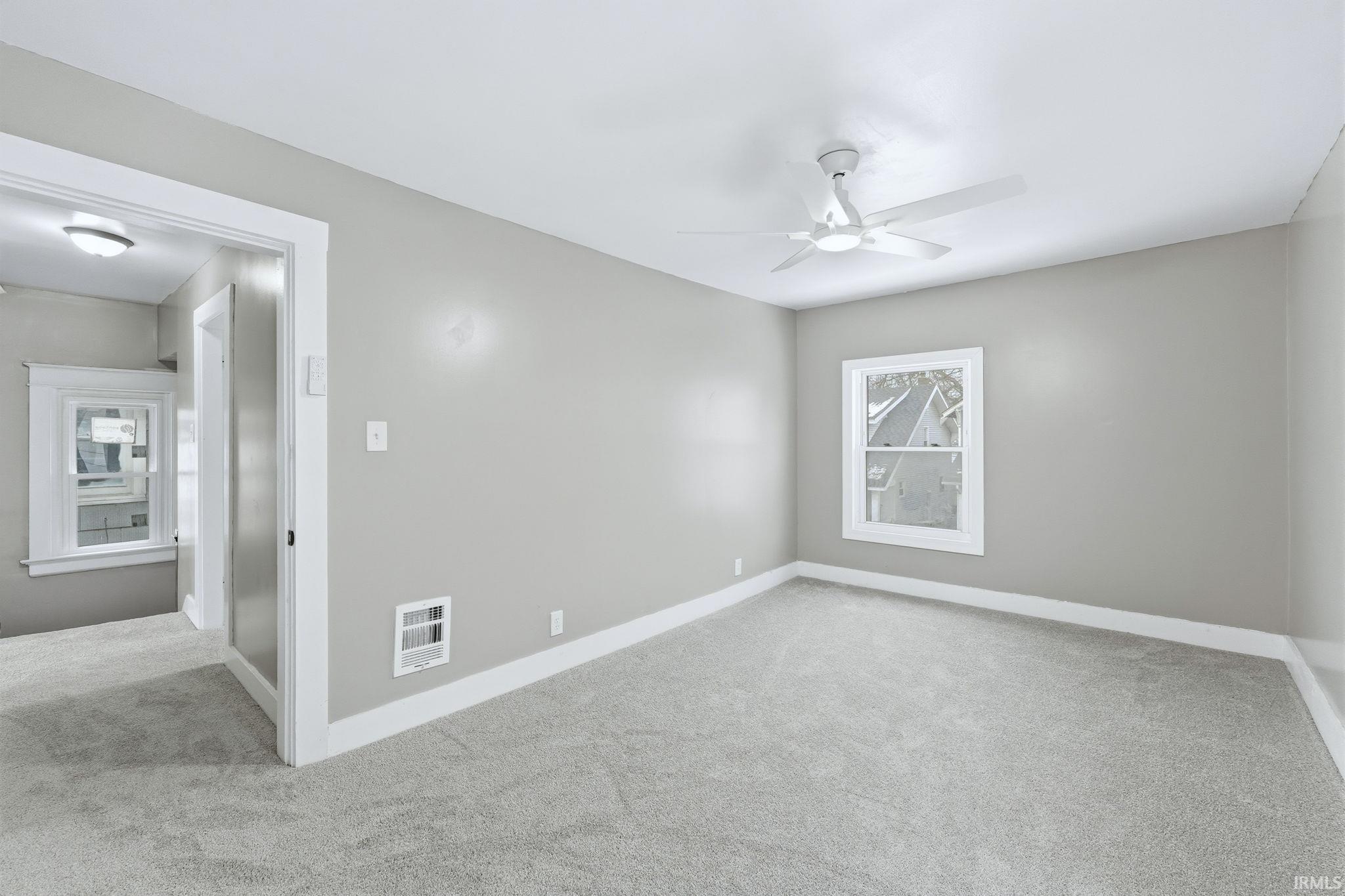 Carpeted empty room featuring baseboards and a ceiling fan