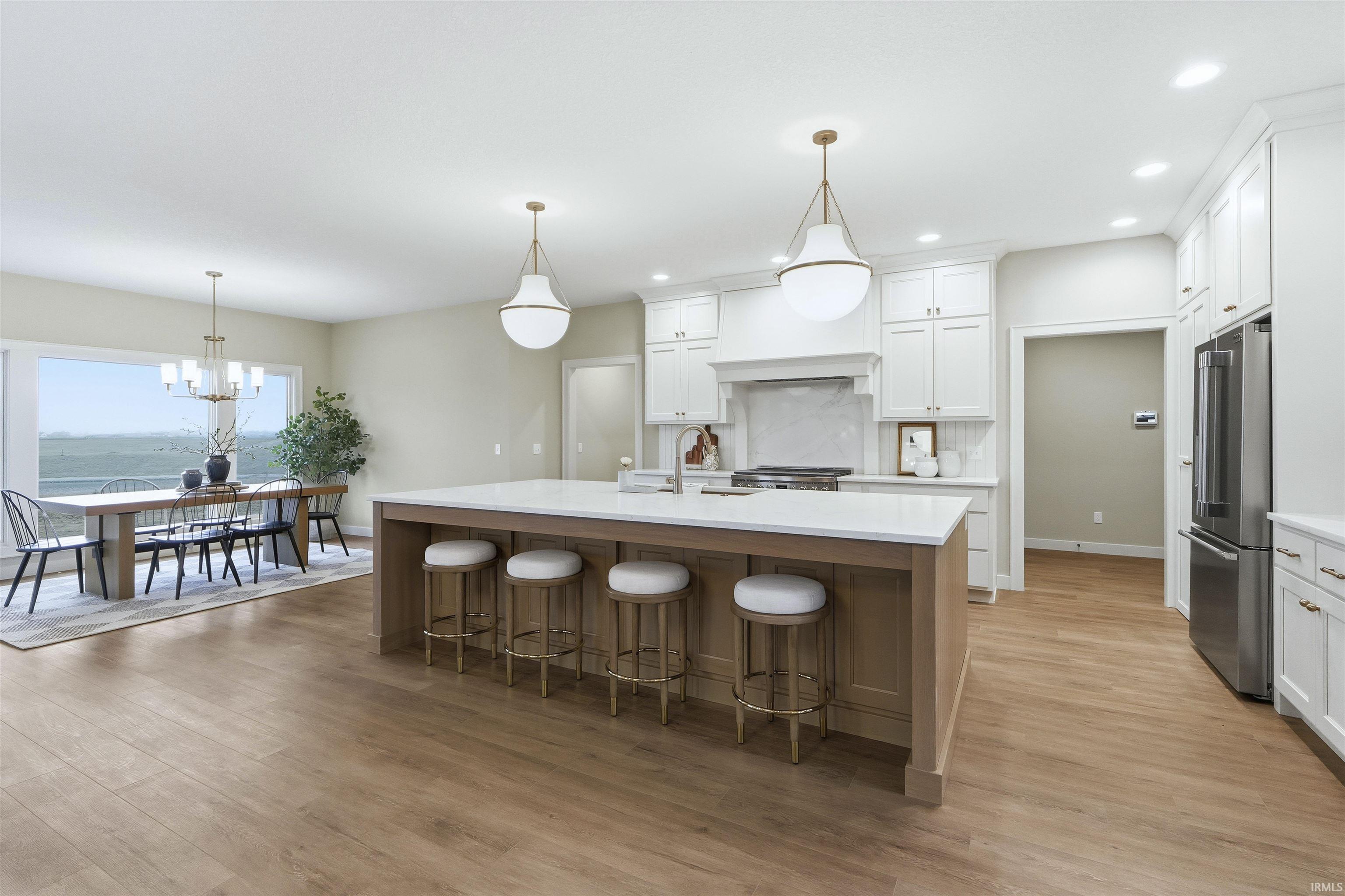 Kitchen featuring a kitchen island with sink, a kitchen bar, high quality fridge, hanging light fixtures, and a chandelier