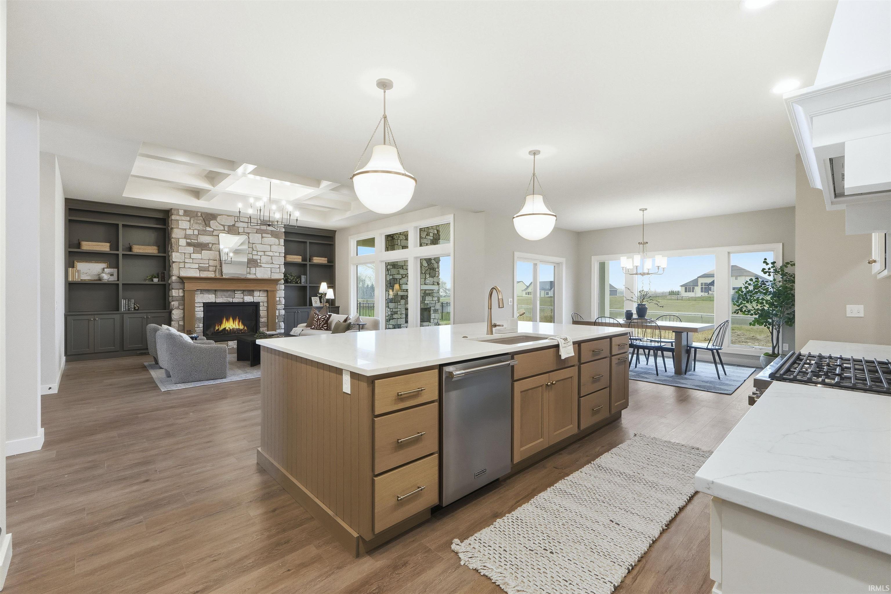 Kitchen with a chandelier, a stone fireplace, built in shelves, open floor plan, and coffered ceiling