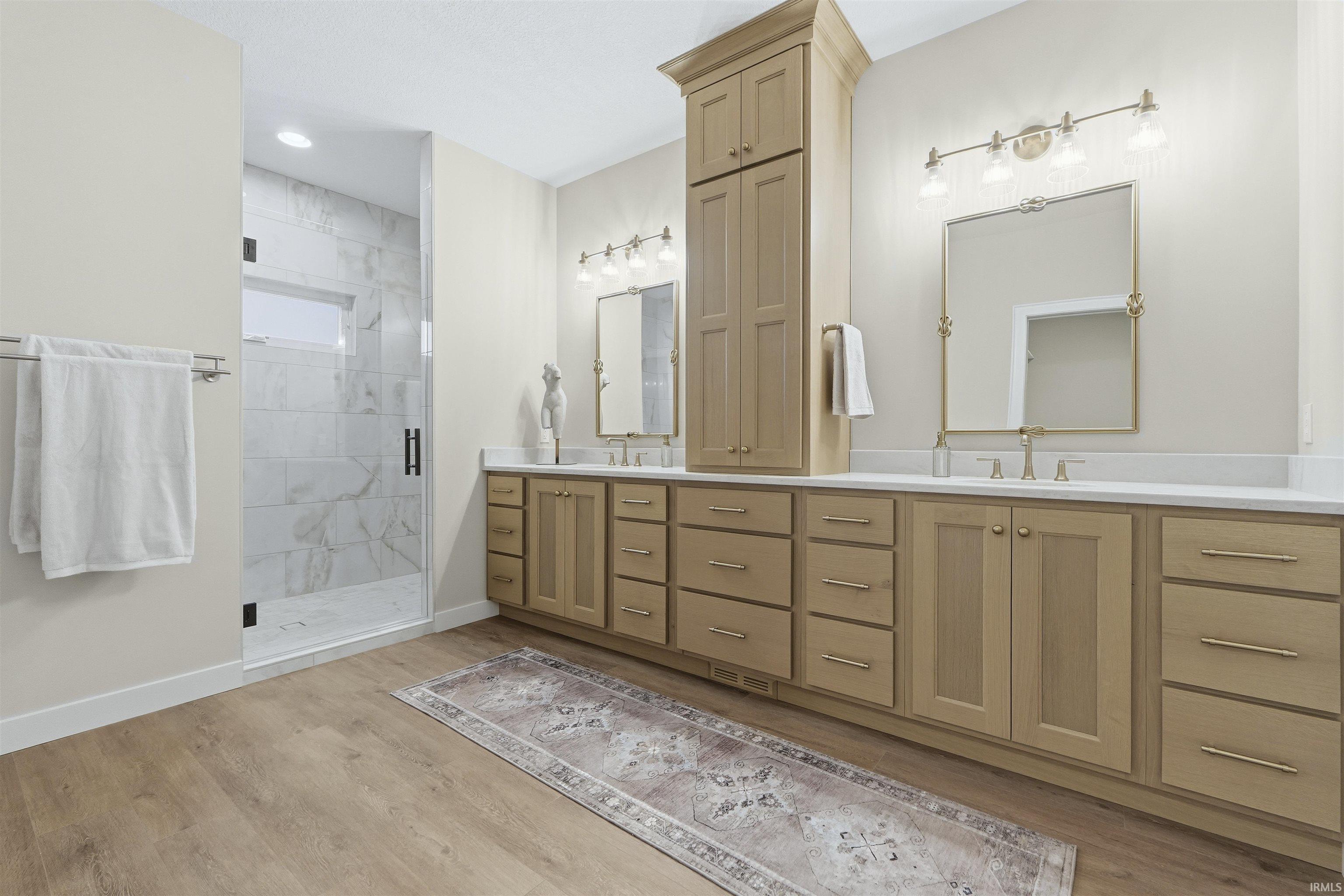 Bathroom with double vanity, light wood-type flooring, and a shower stall