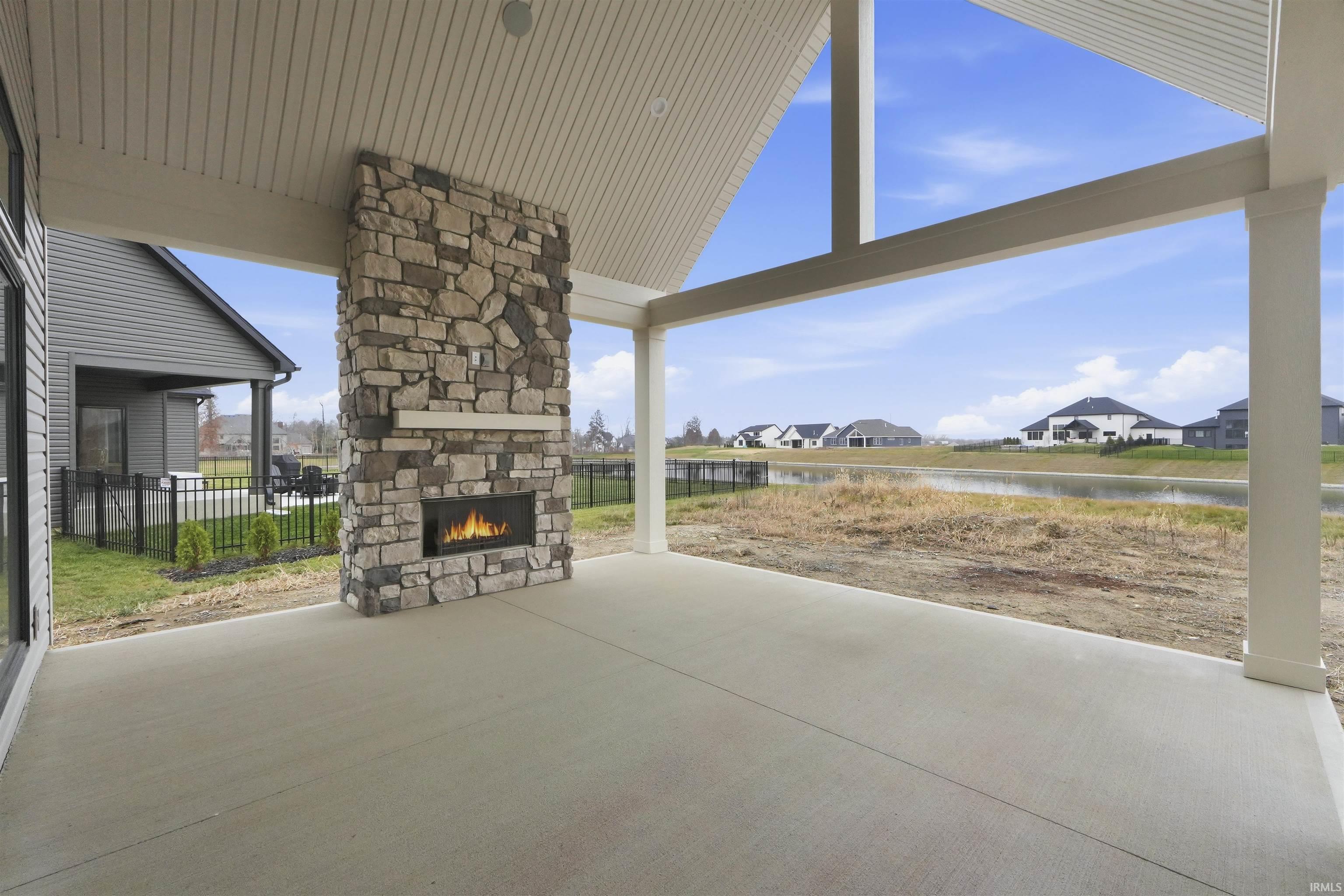 View of patio with a water view, an outdoor stone fireplace, and a residential view