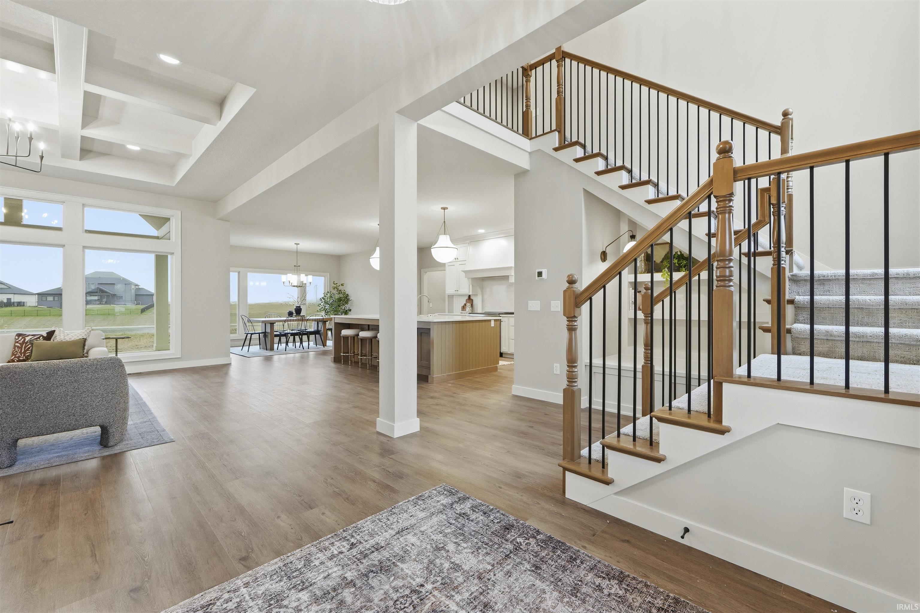 Entryway featuring a chandelier, coffered ceiling, light wood-style flooring, beamed ceiling, and stairway