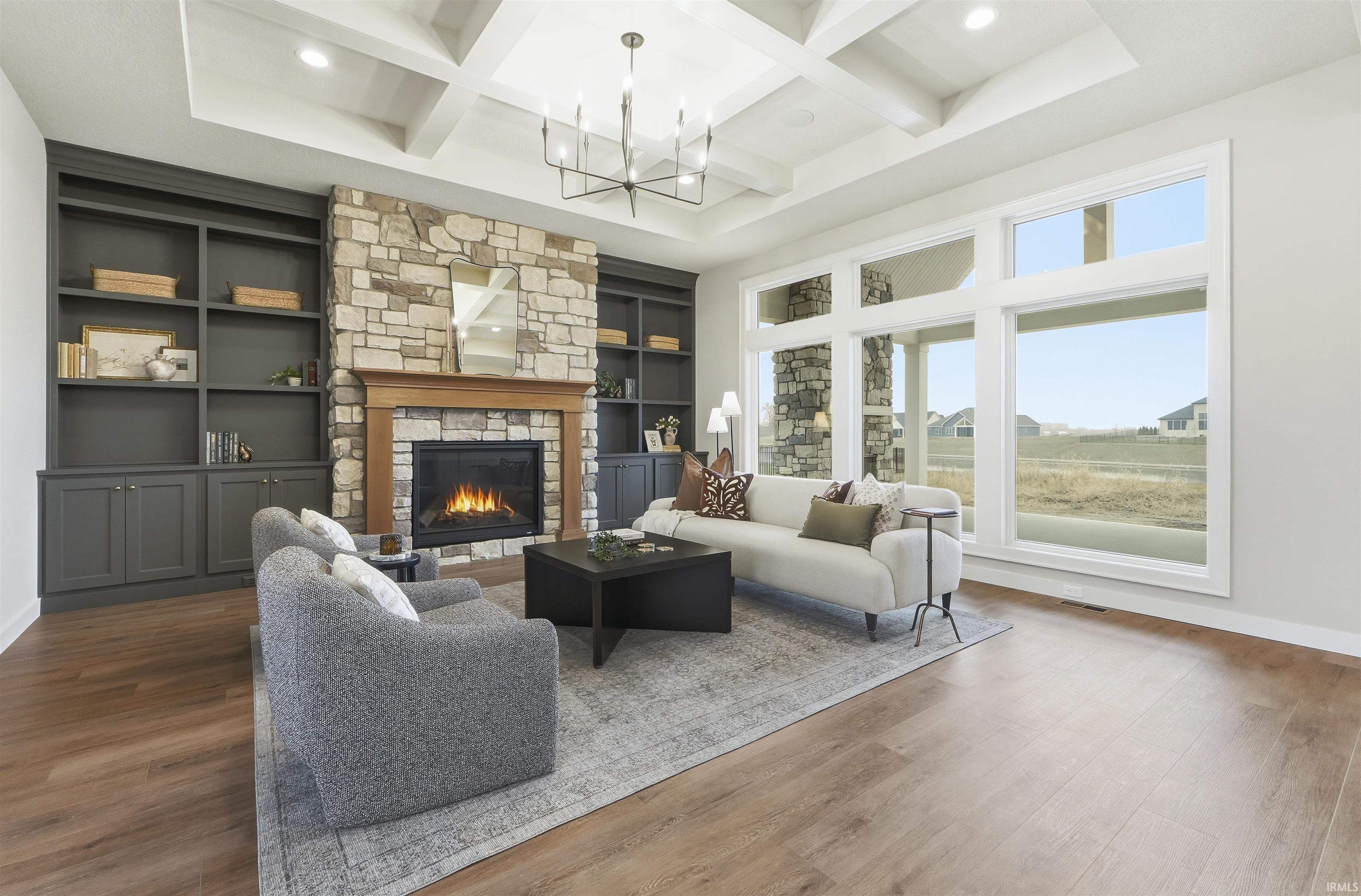 Living area featuring coffered ceiling, wood finished floors, beam ceiling, built in features, and a fireplace