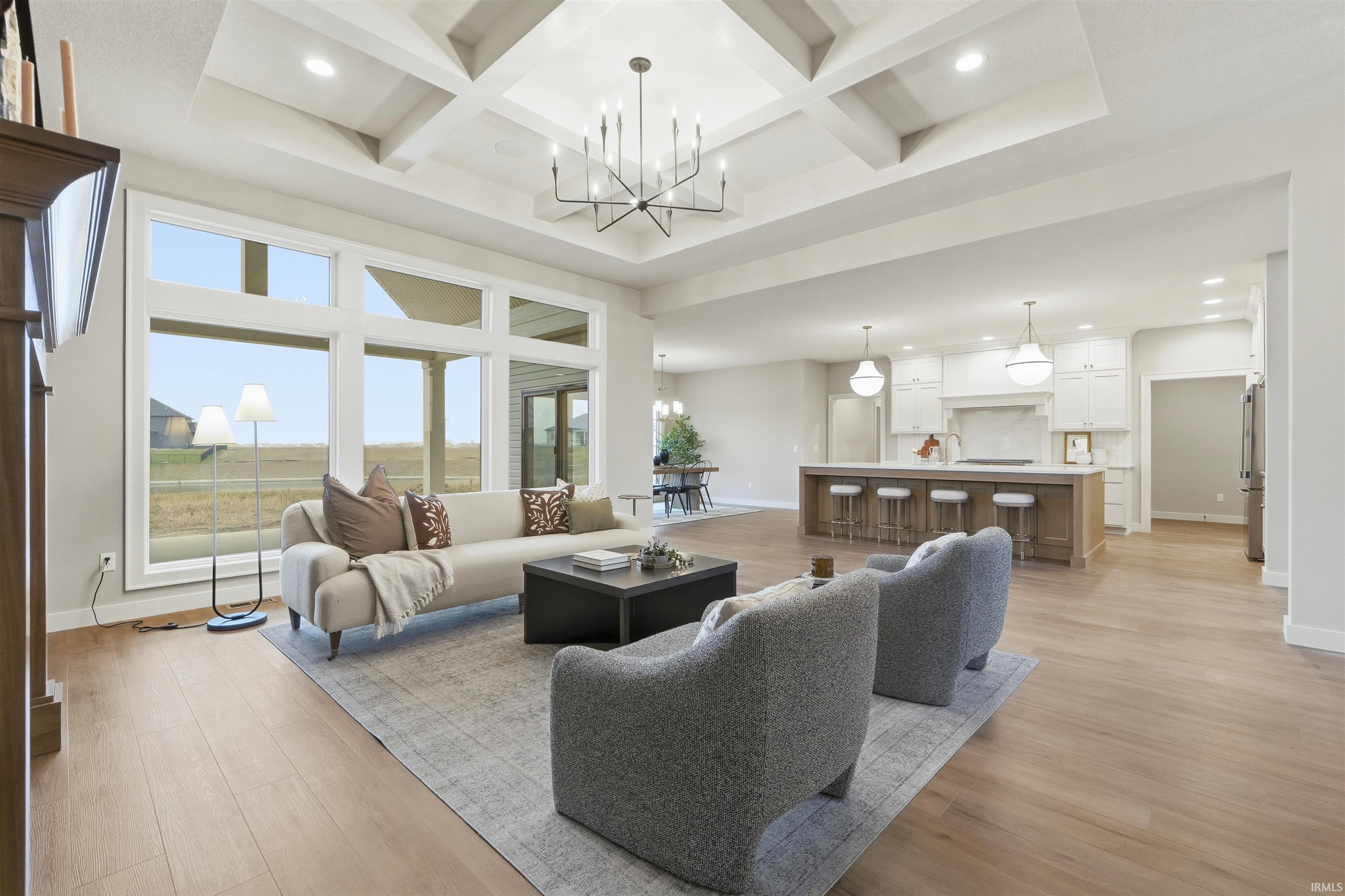 Living area with coffered ceiling, a chandelier, light wood-type flooring, beam ceiling, and a towering ceiling