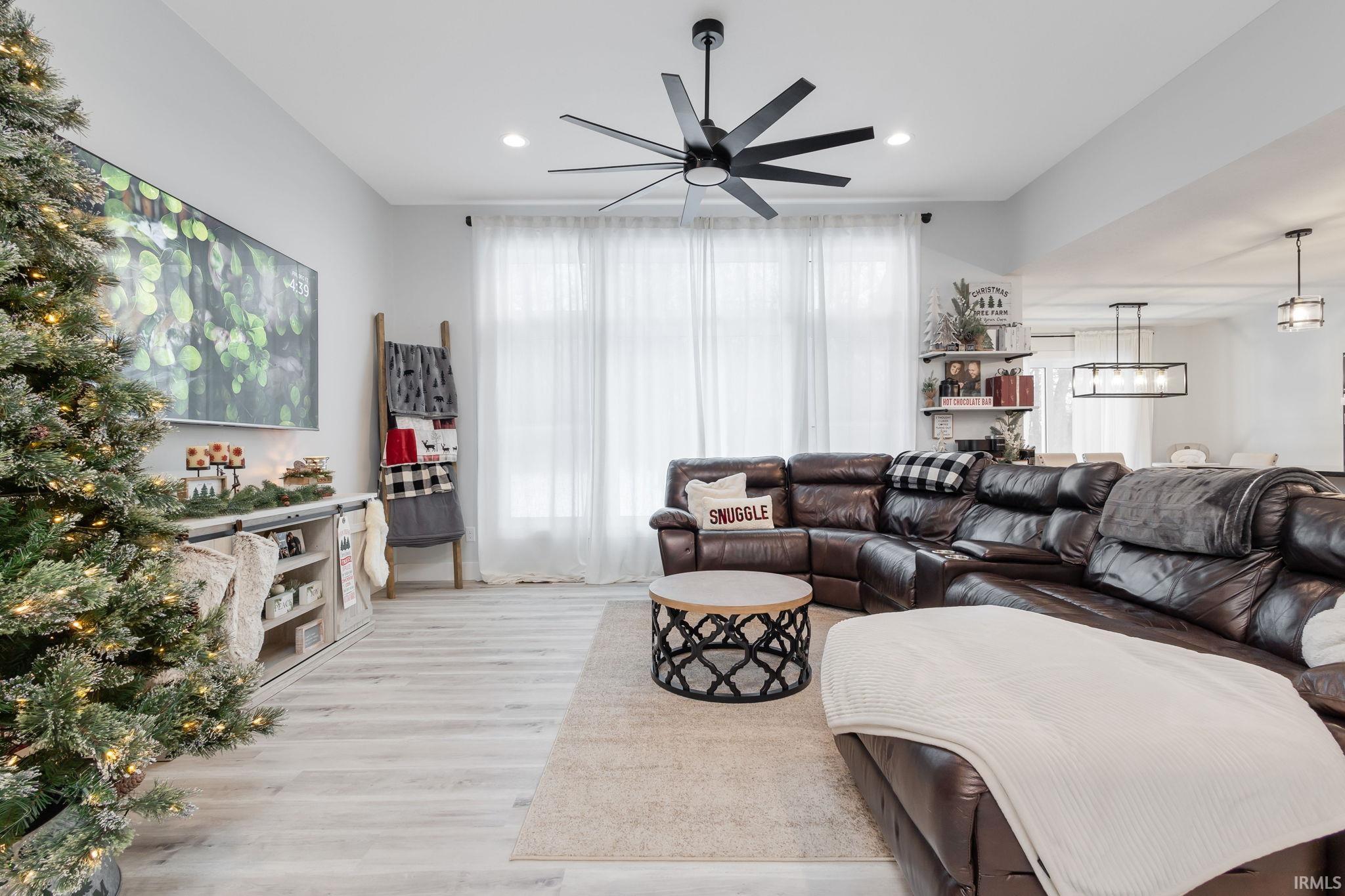 Living area featuring wood finished floors, ceiling fan, a chandelier, and recessed lighting
