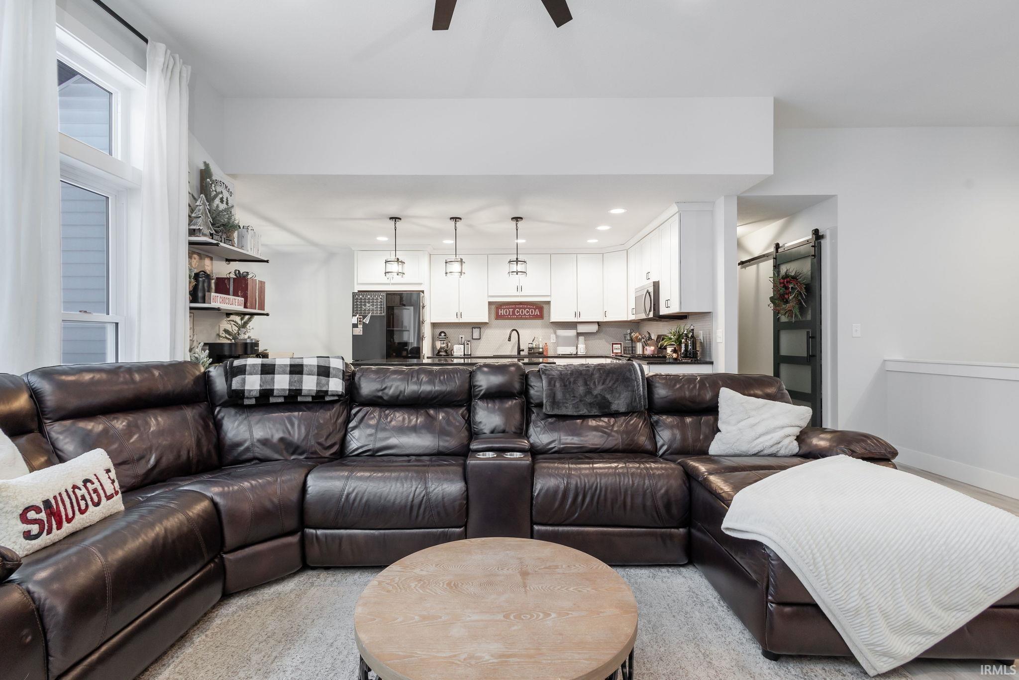 Living room featuring a barn door, a ceiling fan, and recessed lighting