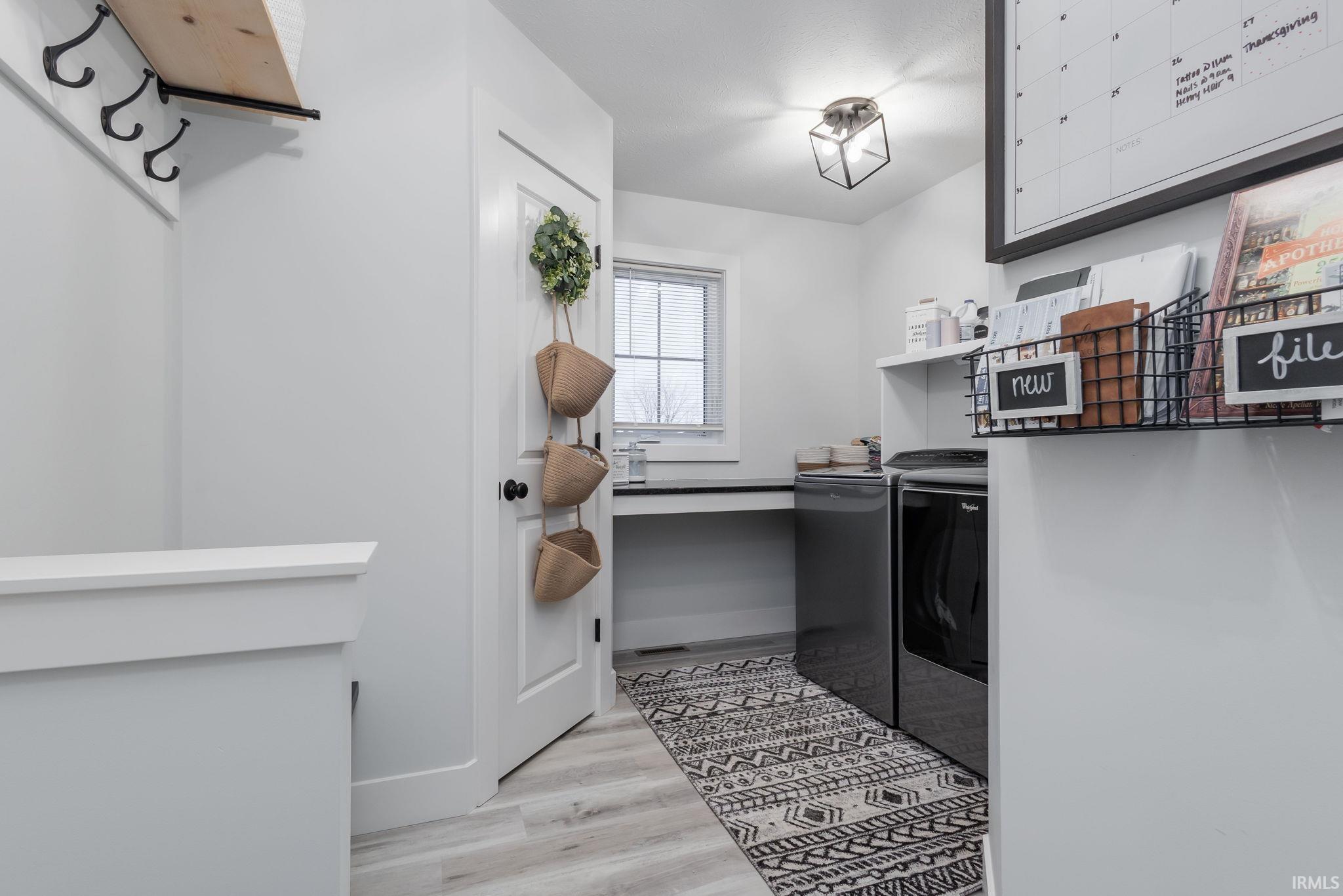 Laundry room featuring light wood-style floors and washing machine and clothes dryer