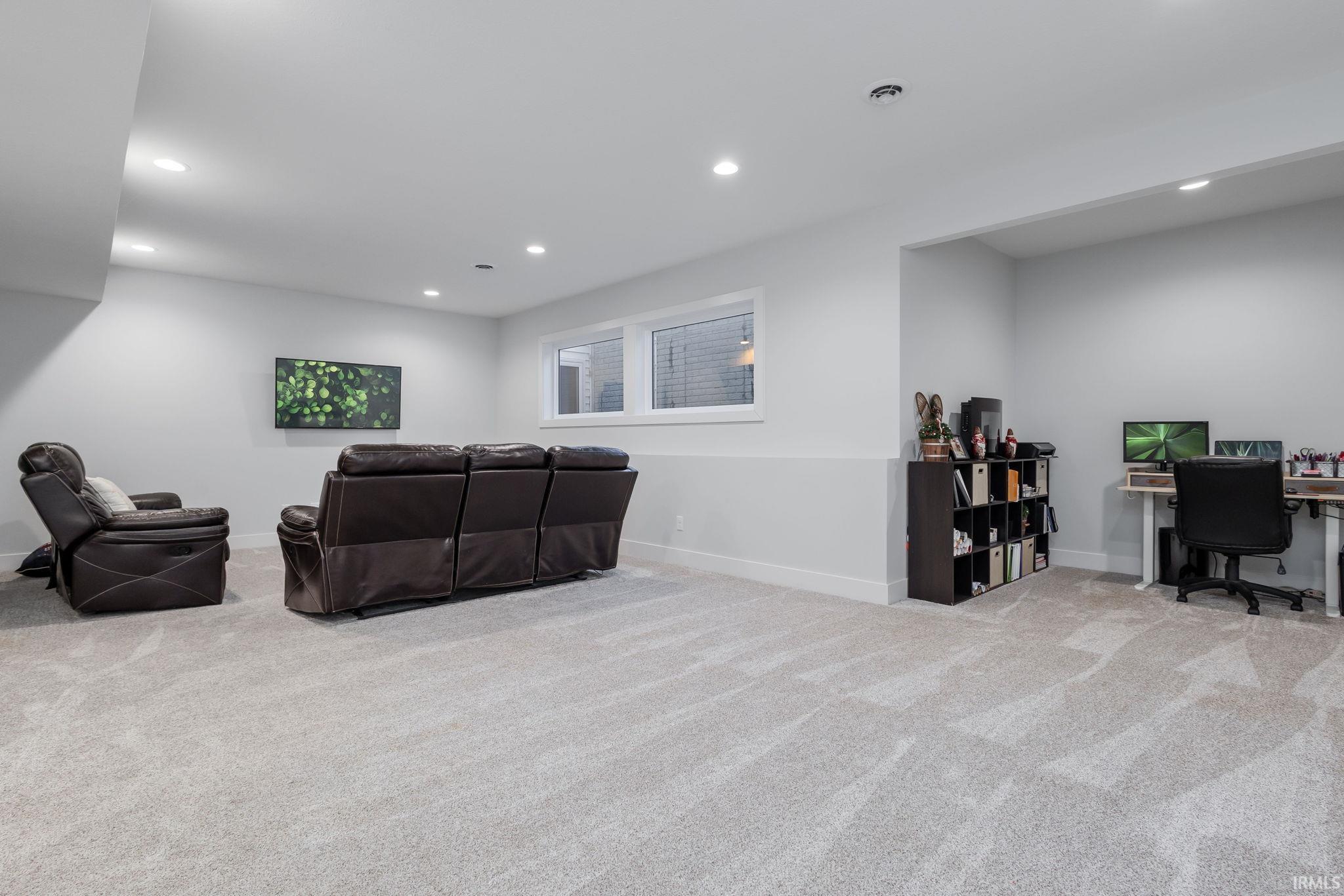 Living room with a desk, light colored carpet, and recessed lighting