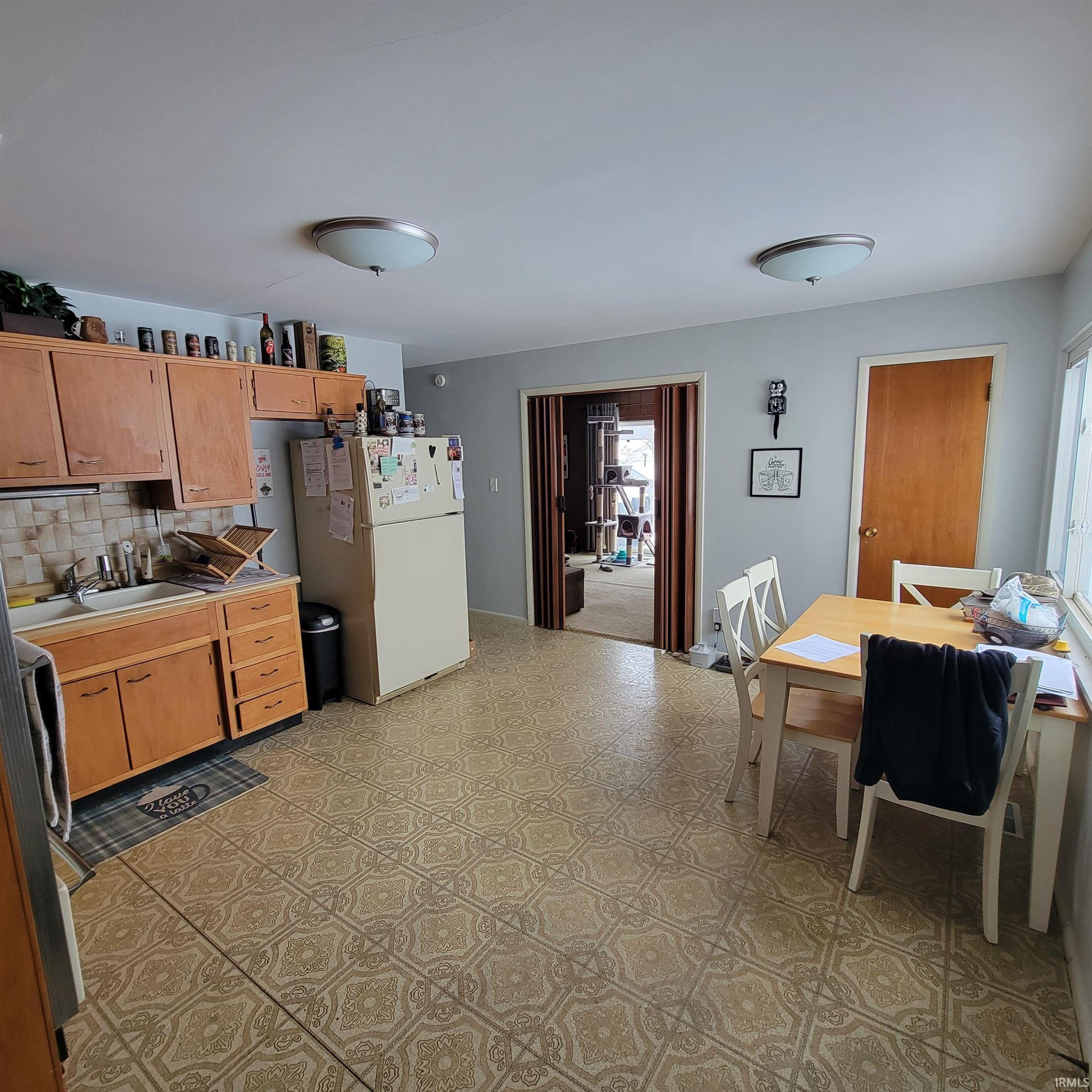 Kitchen with freestanding refrigerator, decorative backsplash, light countertops, and light floors