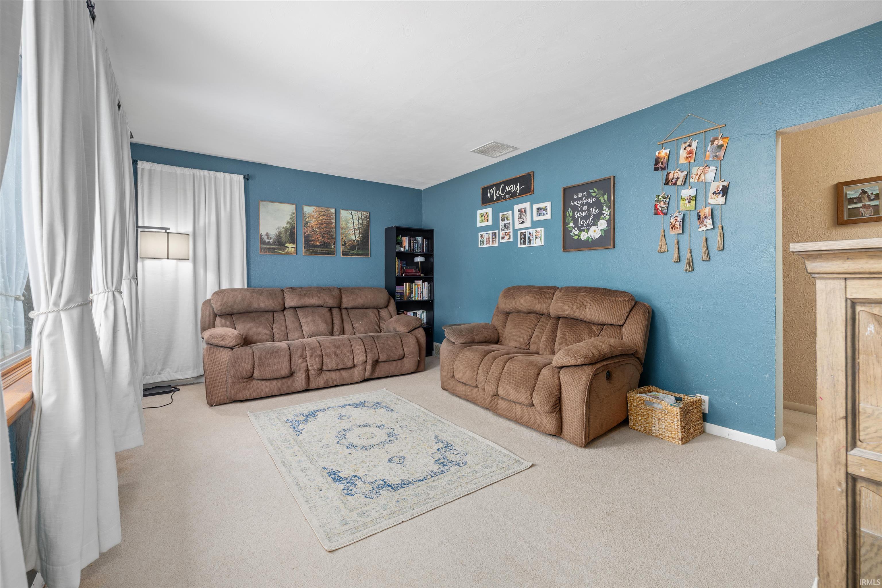Living area featuring carpet flooring and a textured wall