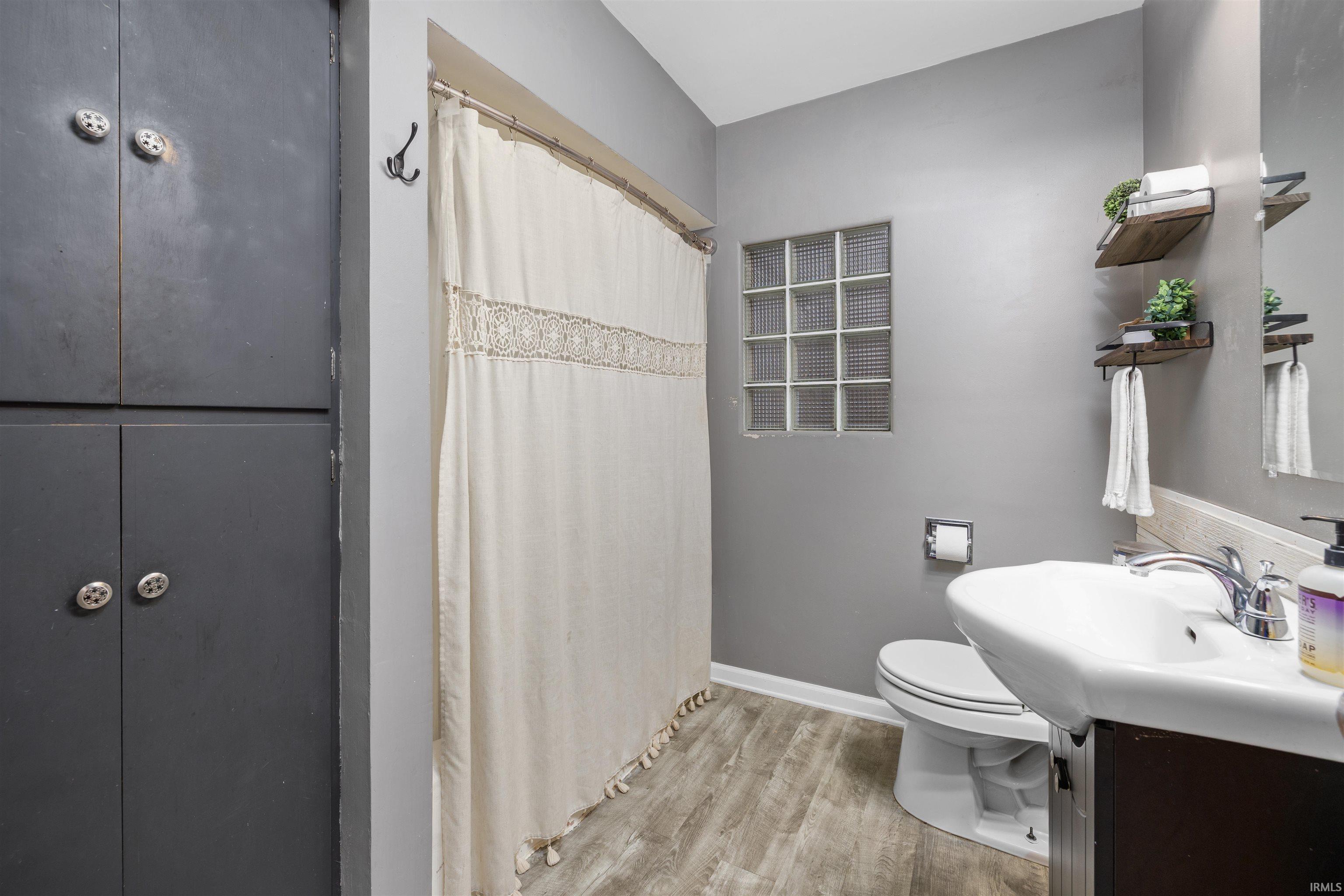 Bathroom with vanity, a shower with shower curtain, and light wood-style flooring